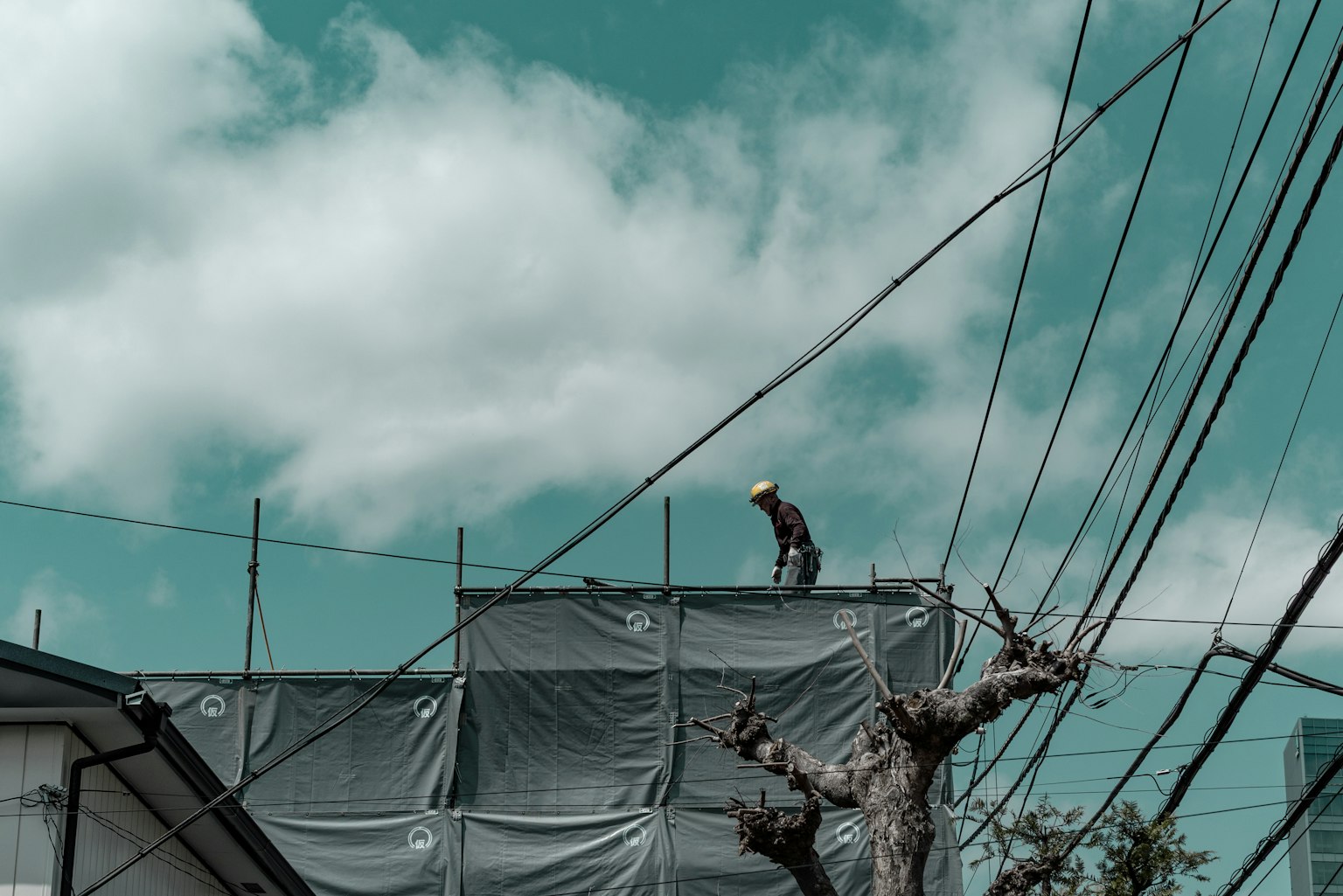 屋根の上に立つ作業者と青い空と雲の背景