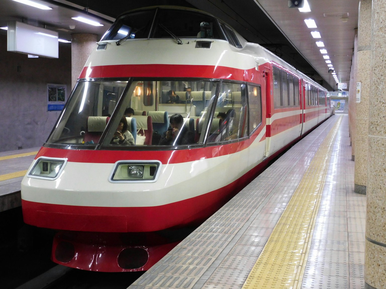 Un treno moderno rosso e bianco è fermo in una stazione