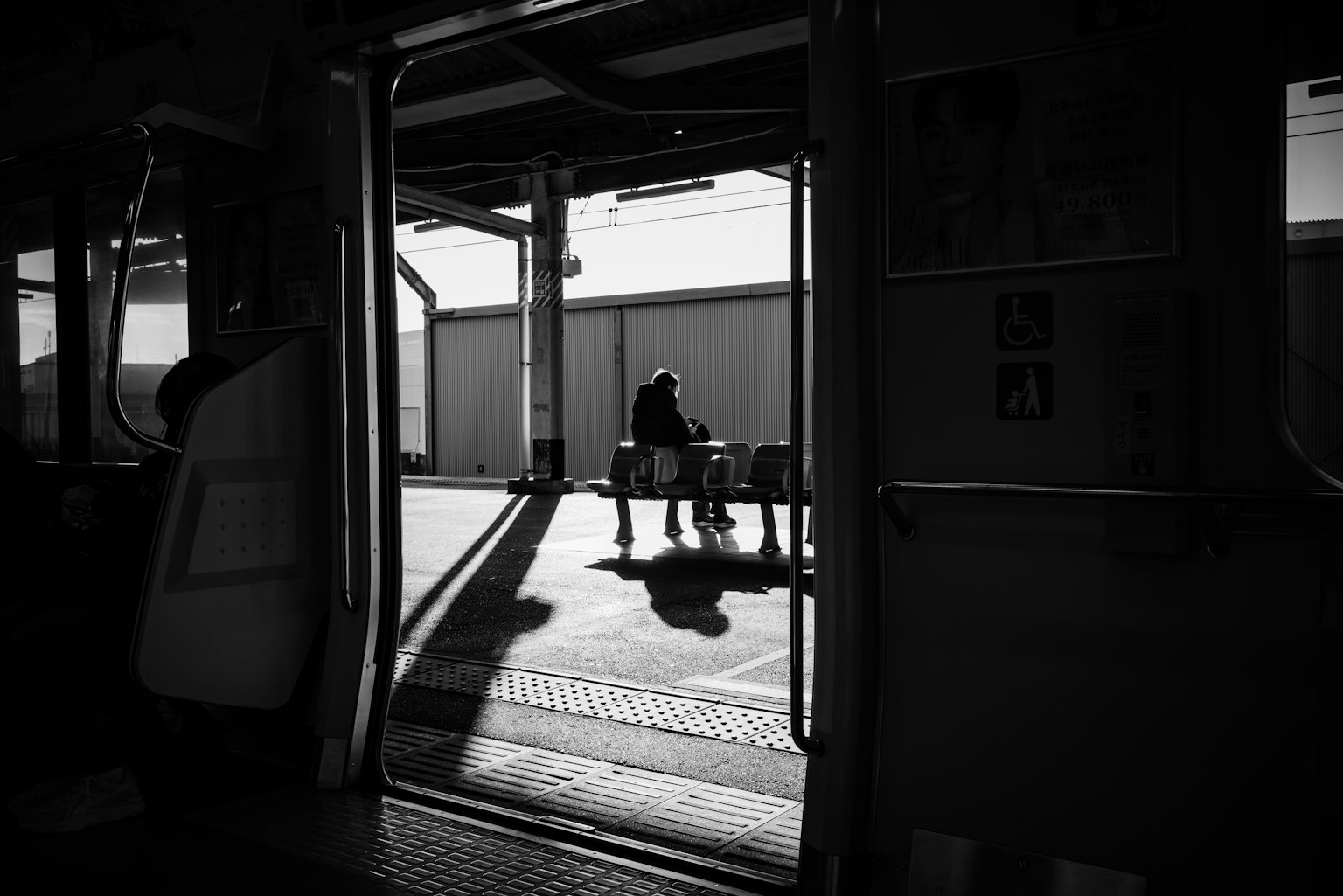 Silhouette d'une personne assise sur un quai dans une photo en noir et blanc