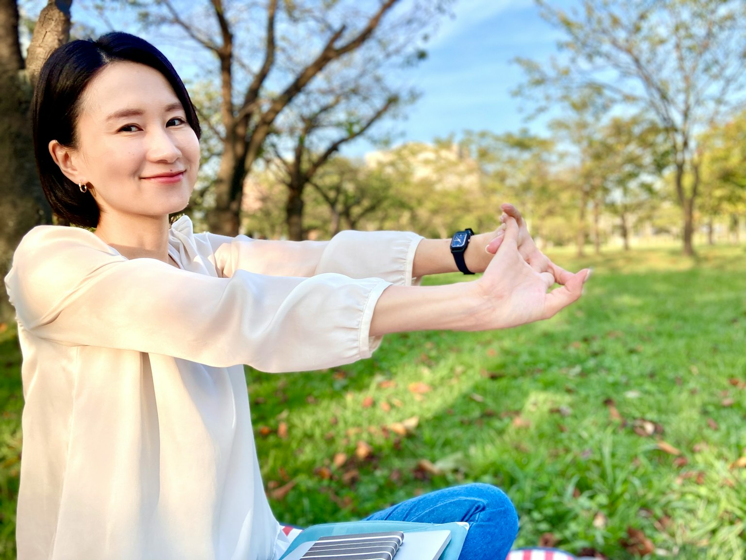 Eine Frau dehnt sich in einem Park, während sie auf dem Gras sitzt