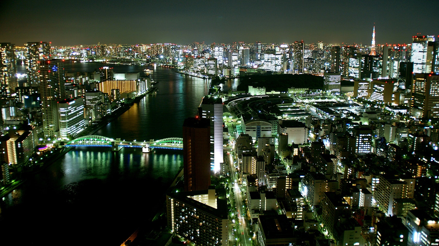 Skyline di Tokyo di notte con edifici illuminati e un fiume