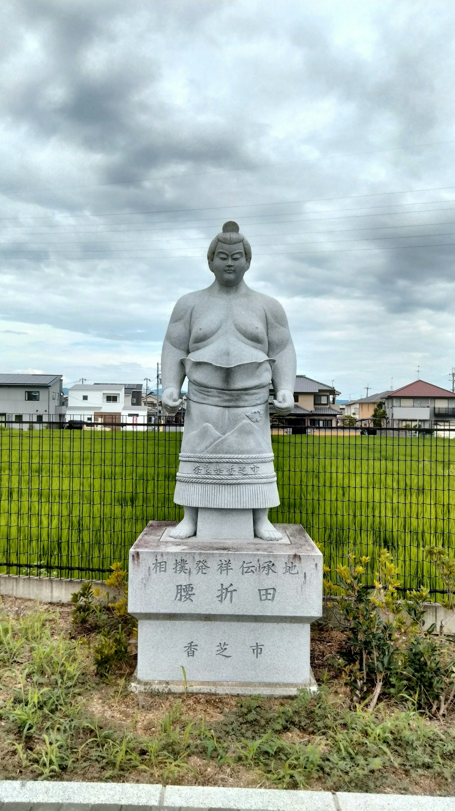 White statue of a samurai standing in a rice field