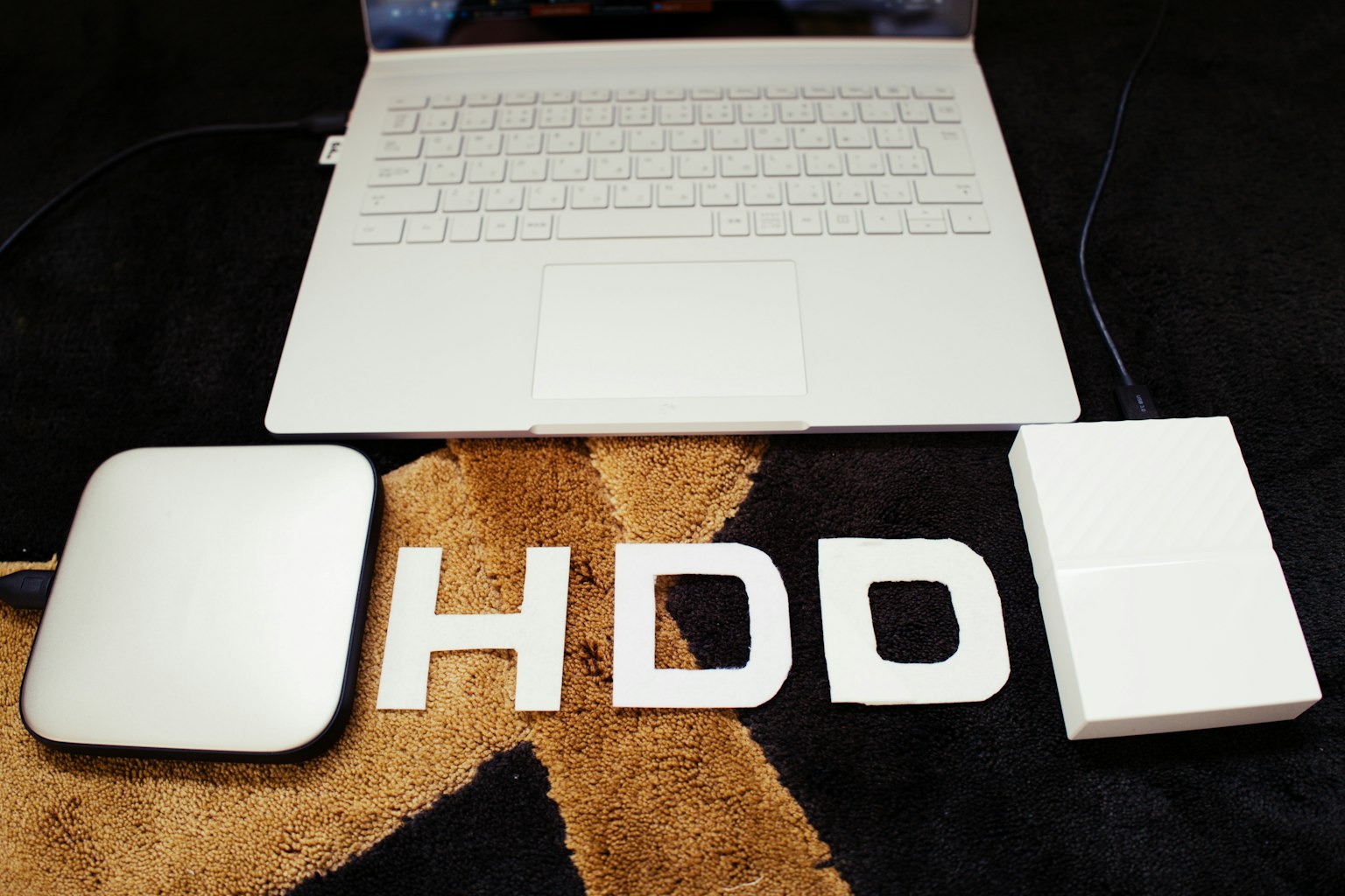 Hình ảnh có một chiếc laptop trắng và ổ cứng ngoài với chữ HDD hiển thị rõ ràng