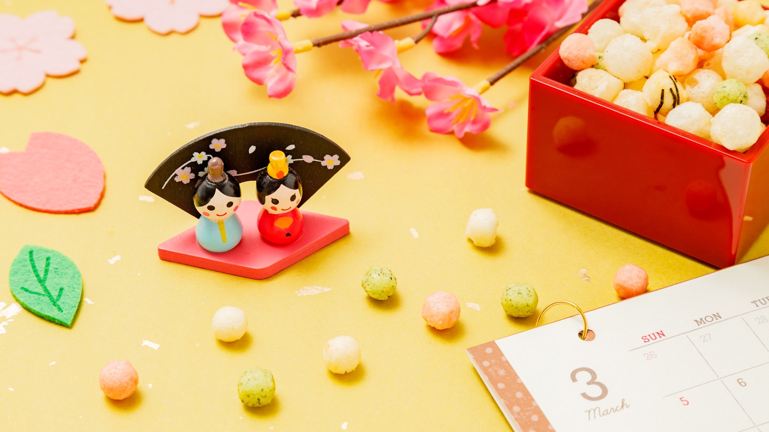 Decoración de Hinamatsuri con pétalos de cerezo y dulces japoneses coloridos esparcidos