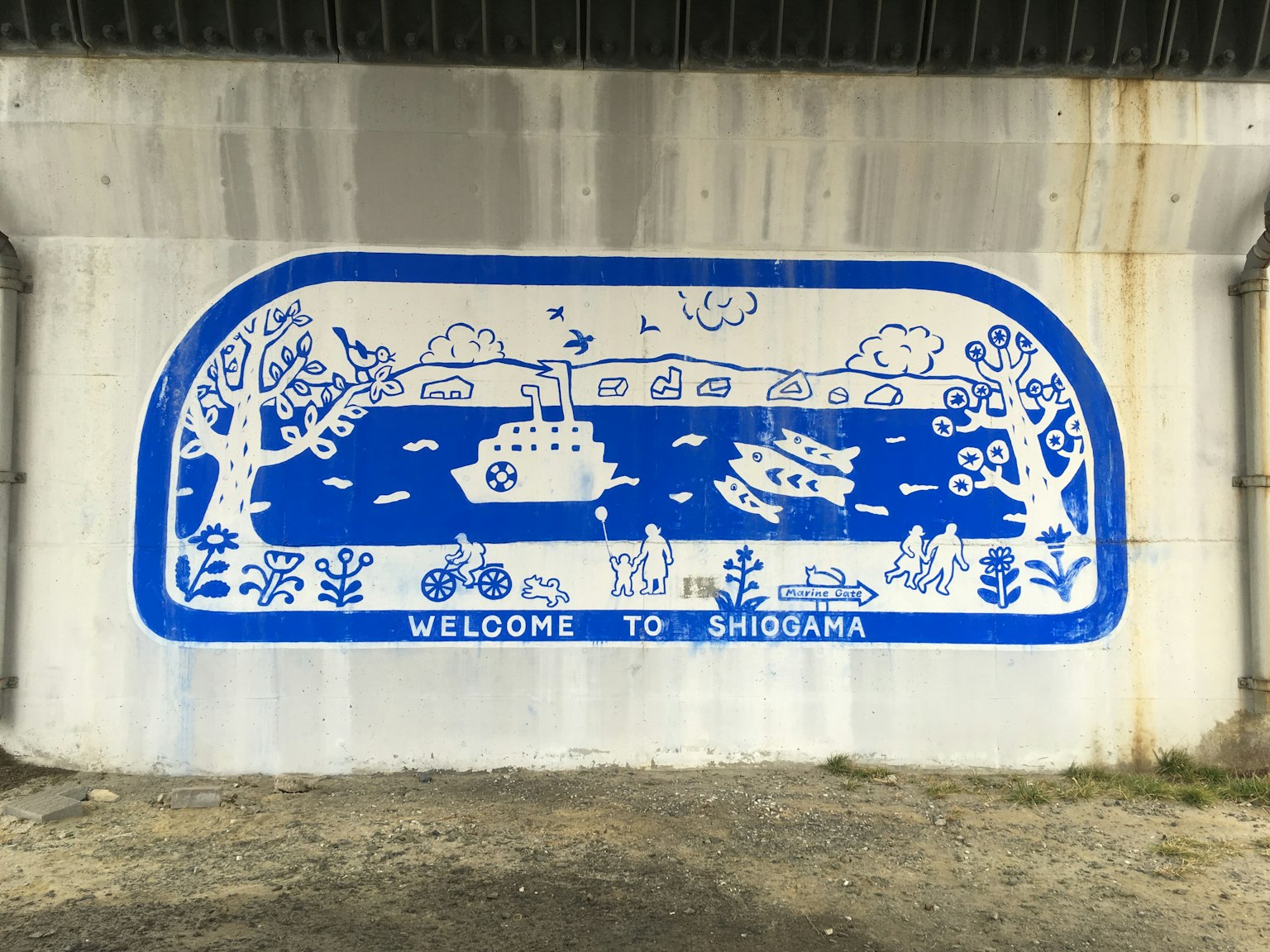 Ein blau-weißes Wandgemälde, das eine Landschaft mit Booten, Fahrrädern und Bäumen darstellt, mit dem Text "WELCOME TO SHIOGAMA" im Vordergrund