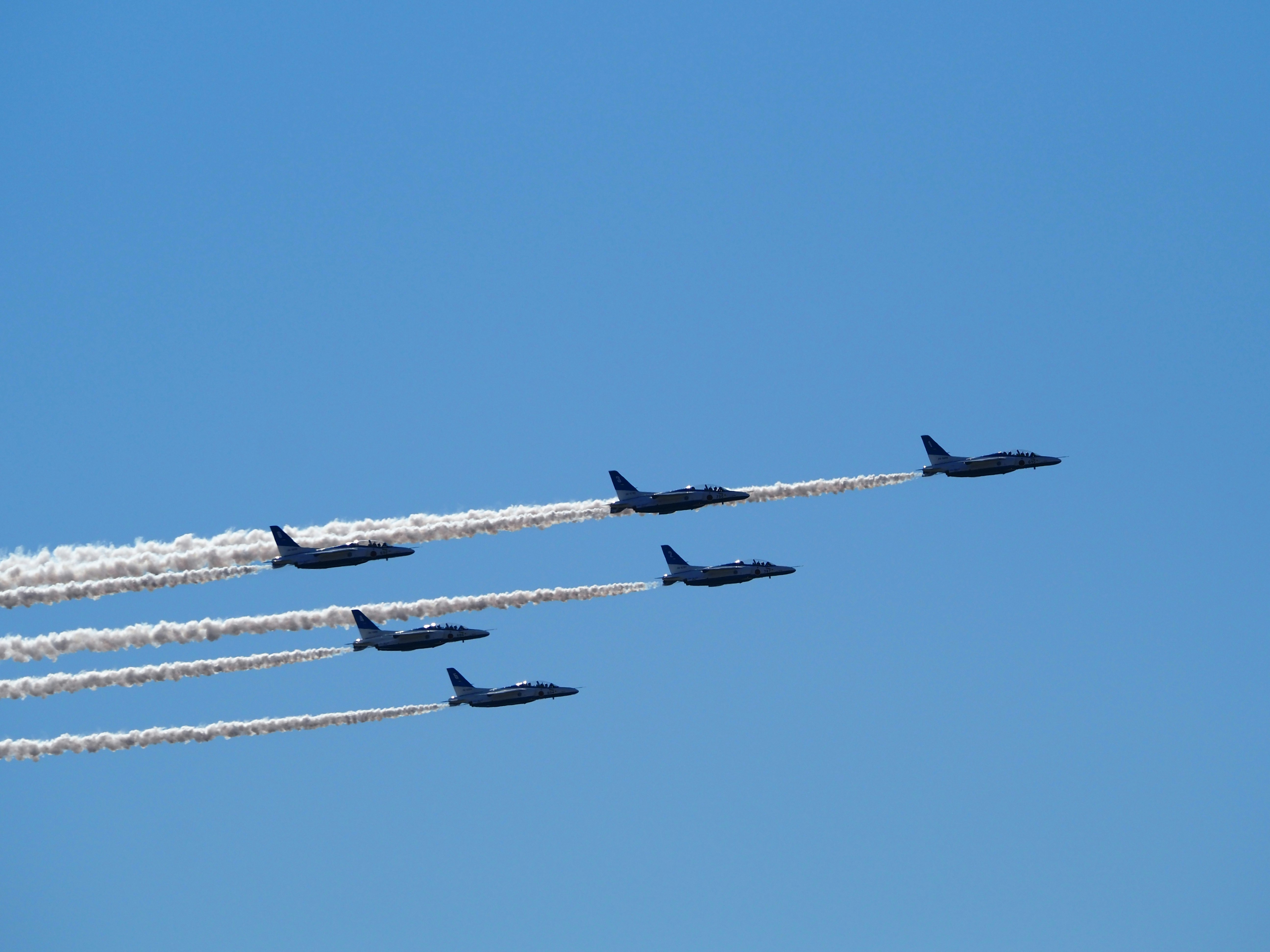 青空を背景にした5機の戦闘機が編隊飛行している様子