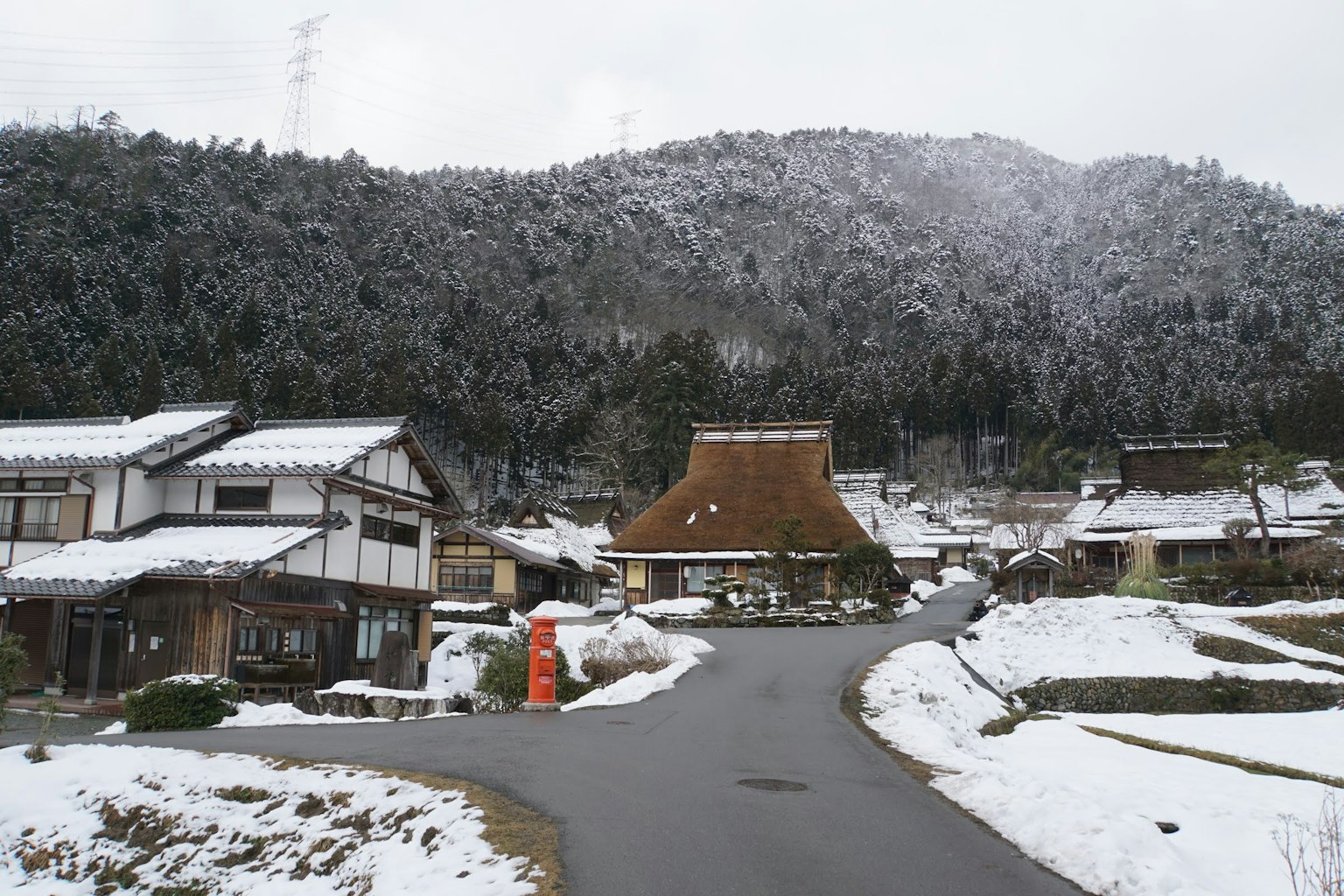 Pemandangan desa tradisional Jepang yang tertutup salju dengan rumah atap jerami dan gunung