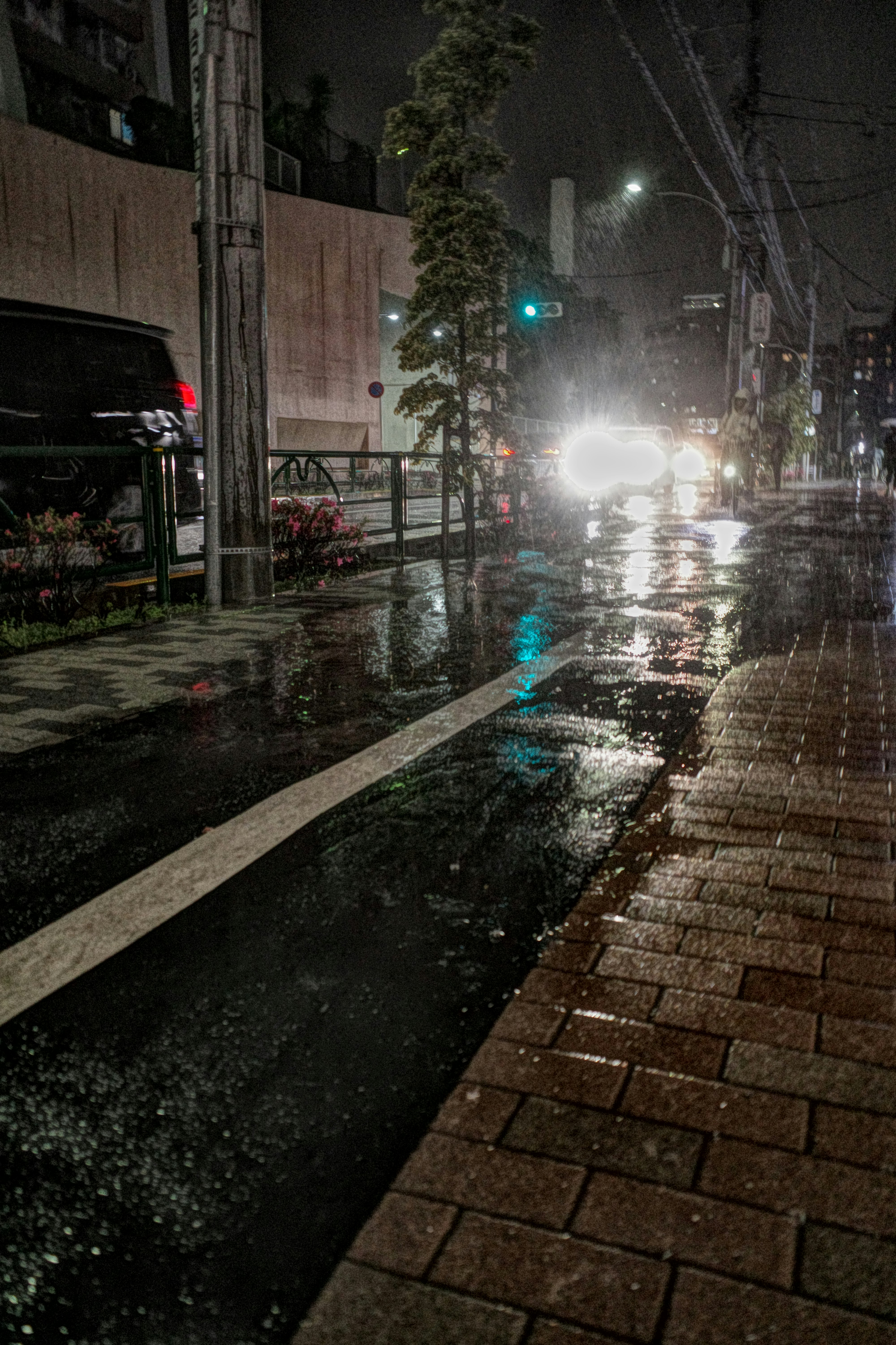 雨夜街角，湿漉漉的人行道上的汽车车灯光