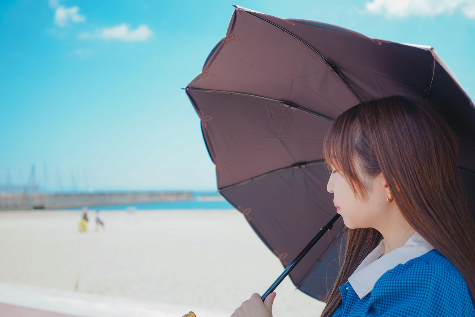 Profil d'une femme tenant un parapluie sous un ciel bleu