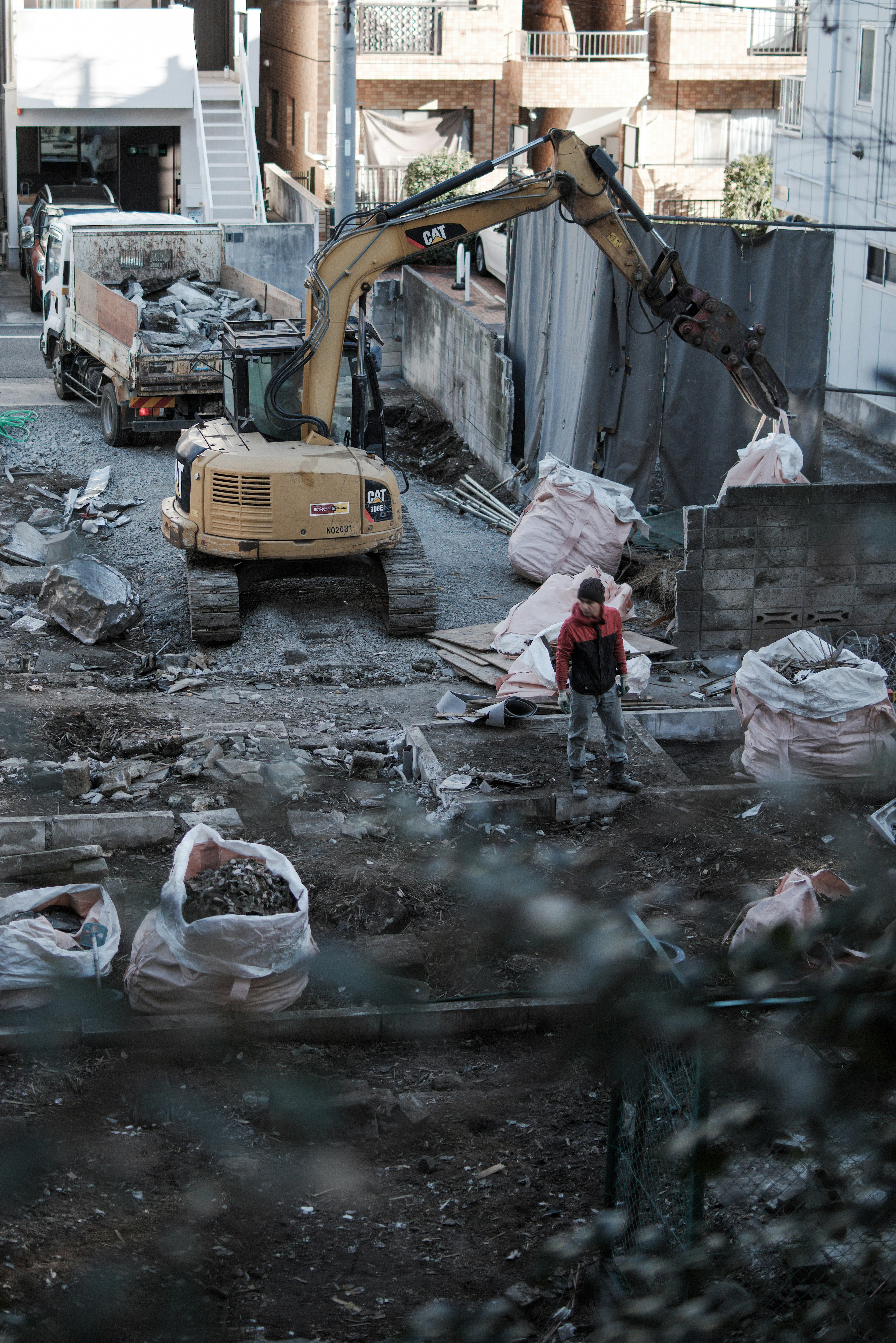 瓦礫の路地に建設重機が並ぶ破壊現場