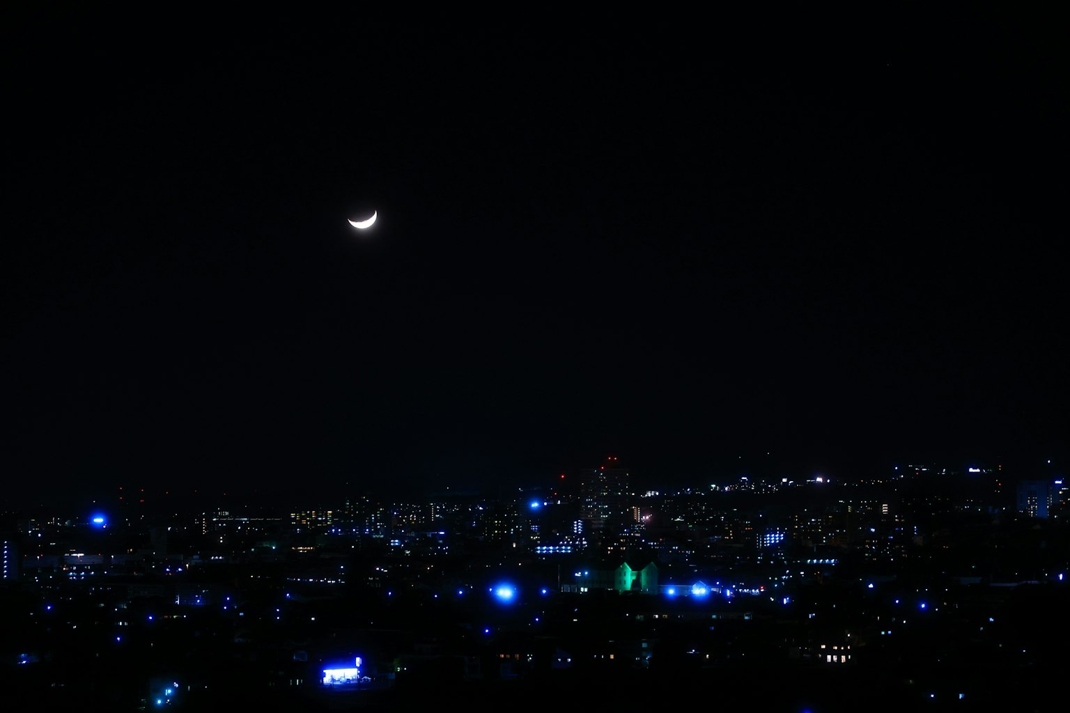 Crescent-Mond im Nachthimmel über einer lebhaften Stadtlandschaft