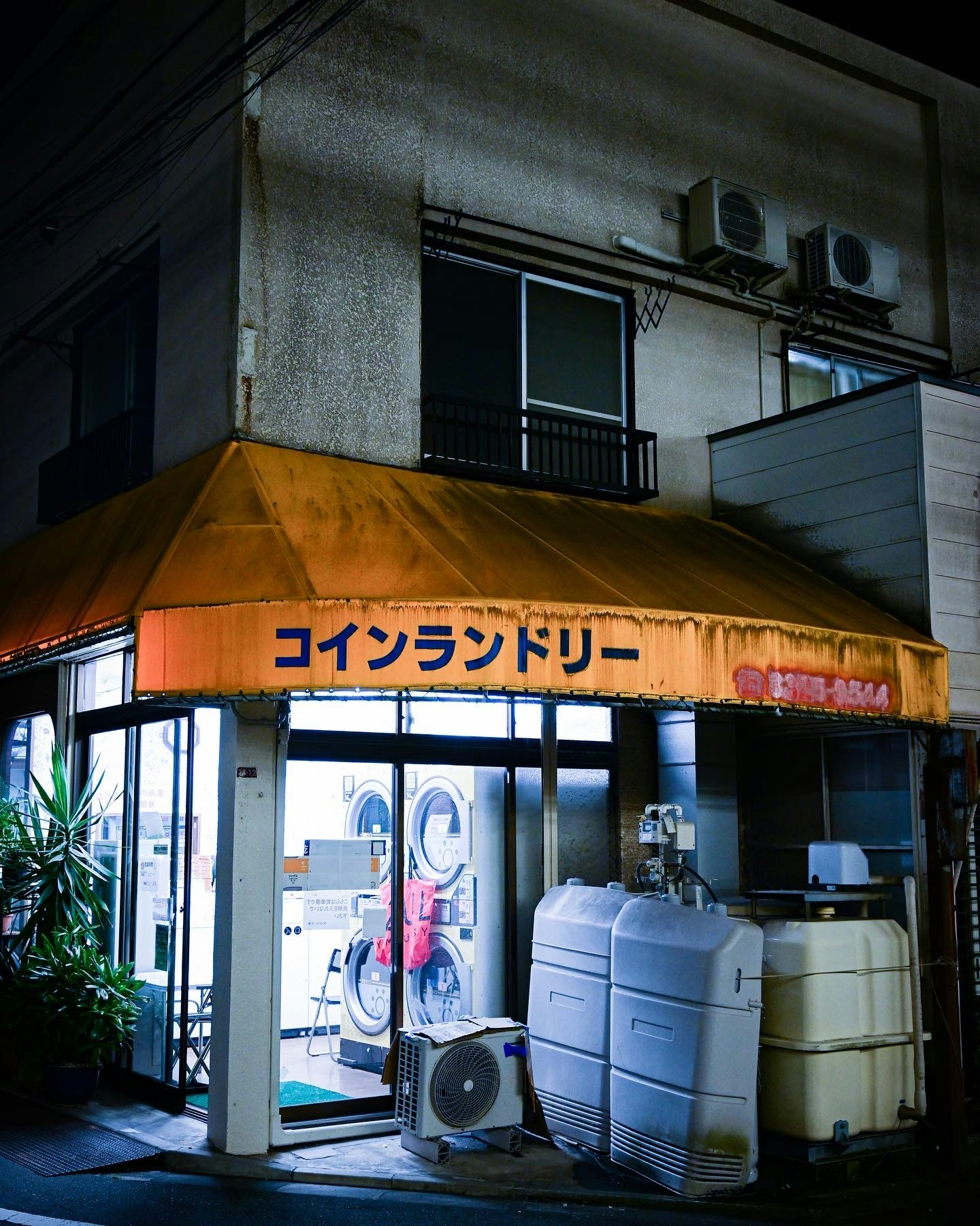 夜晚巷弄裡的自助洗衣店入口與招牌、成排洗衣機