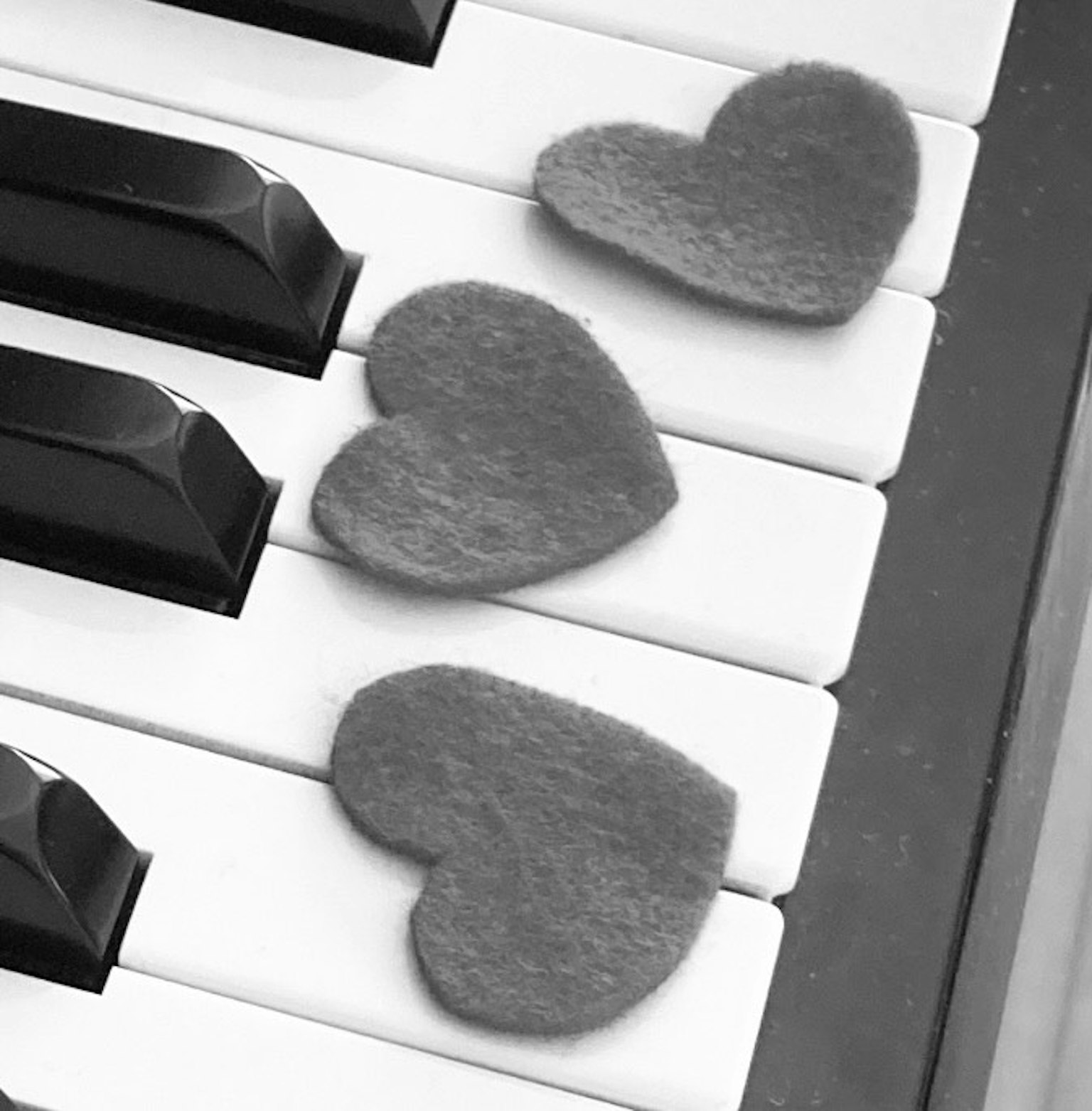 Cuori in feltro grigio posizionati su tasti di pianoforte