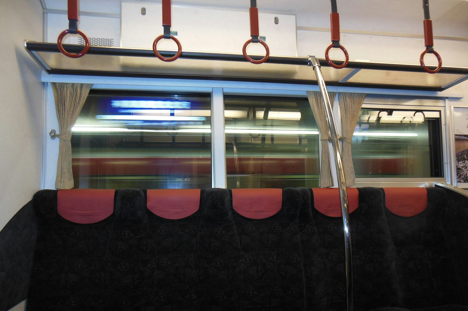 Interior de un tren con asientos y pasamanos