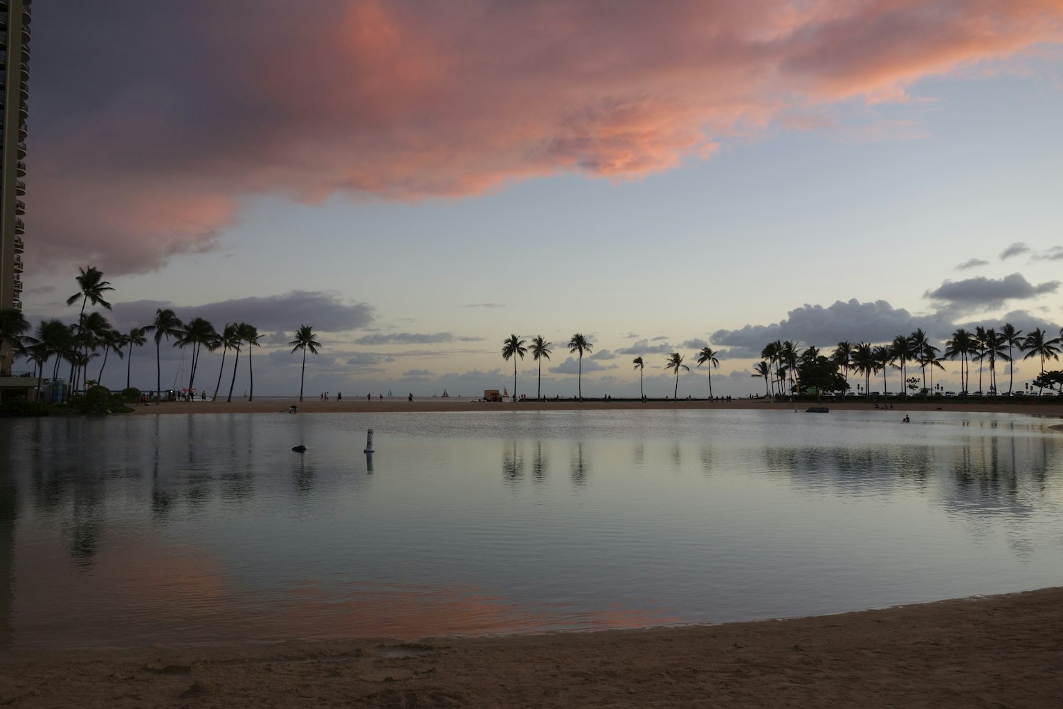 Beautiful sunset beach scene with palm trees reflected on calm water