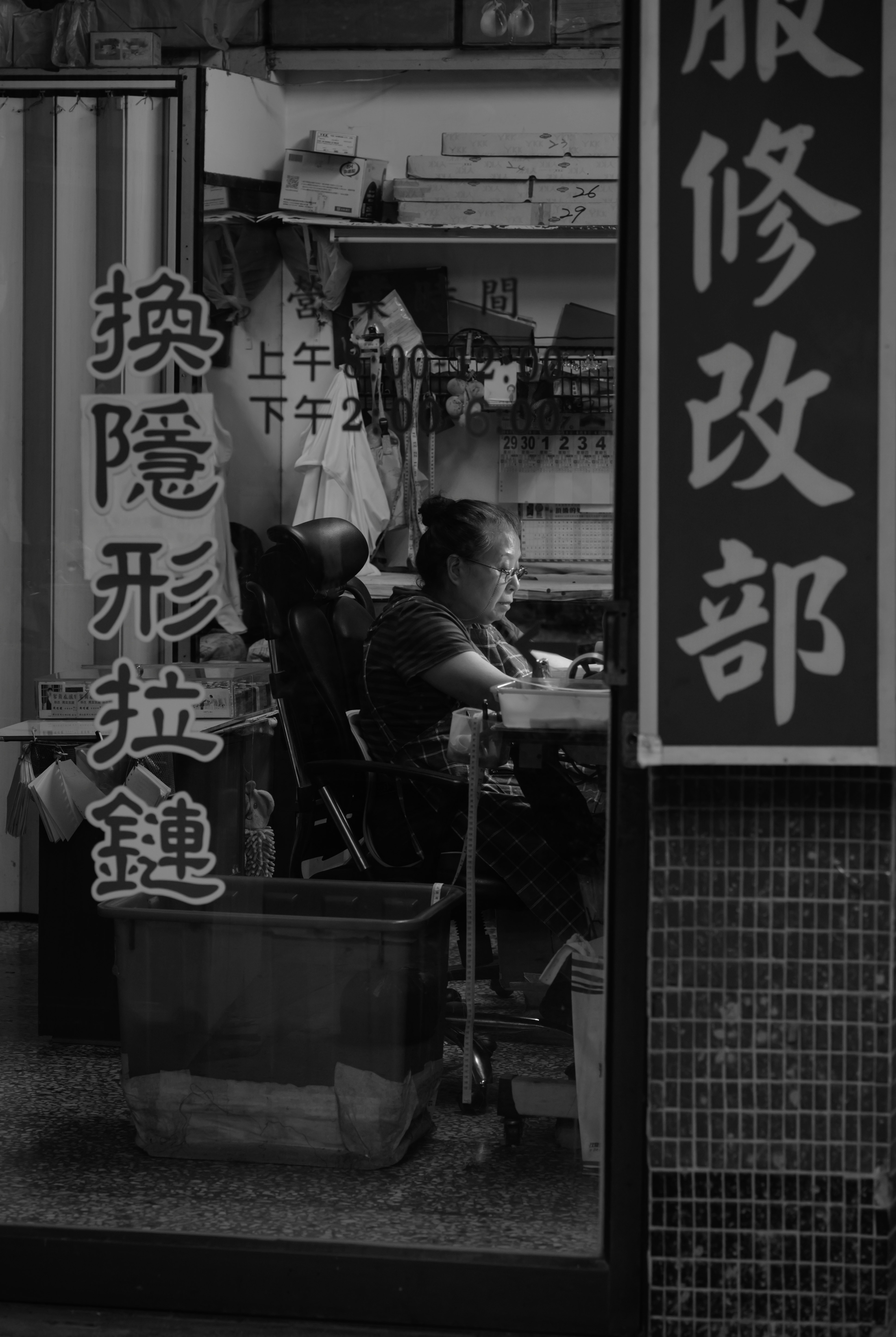 巷弄裡維修店窗邊的工作人員與招牌