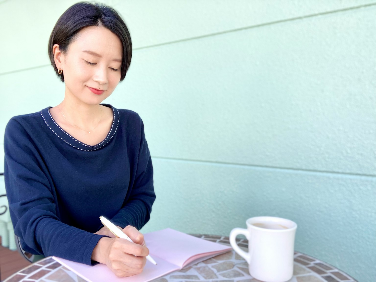 Một người phụ nữ đang viết trong cuốn sổ tại bàn cà phê với một tách cà phê