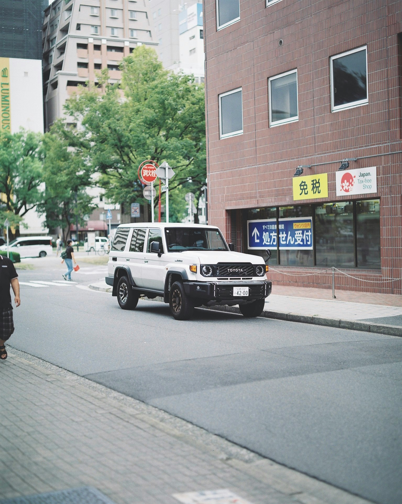 SUV blanc roulant près de panneaux sur un trottoir à un carrefour au Japon