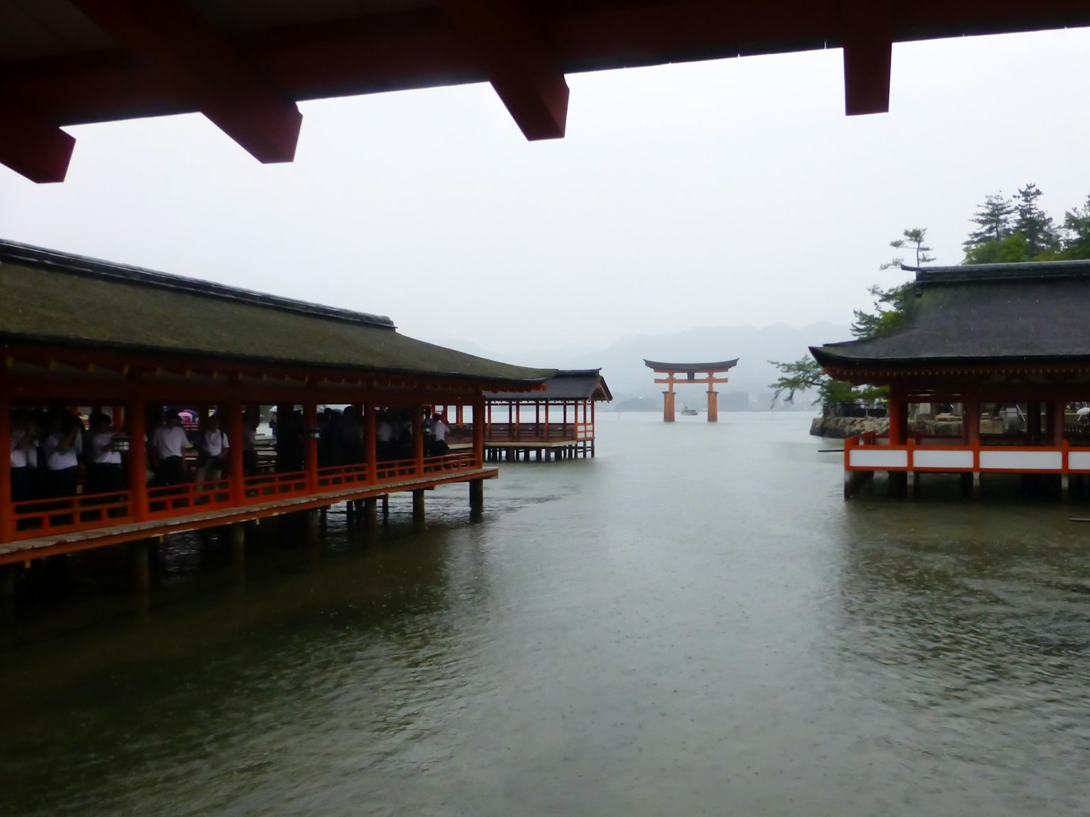 Vista de la puerta torii del Santuario de Itsukushima y edificios sobre el agua