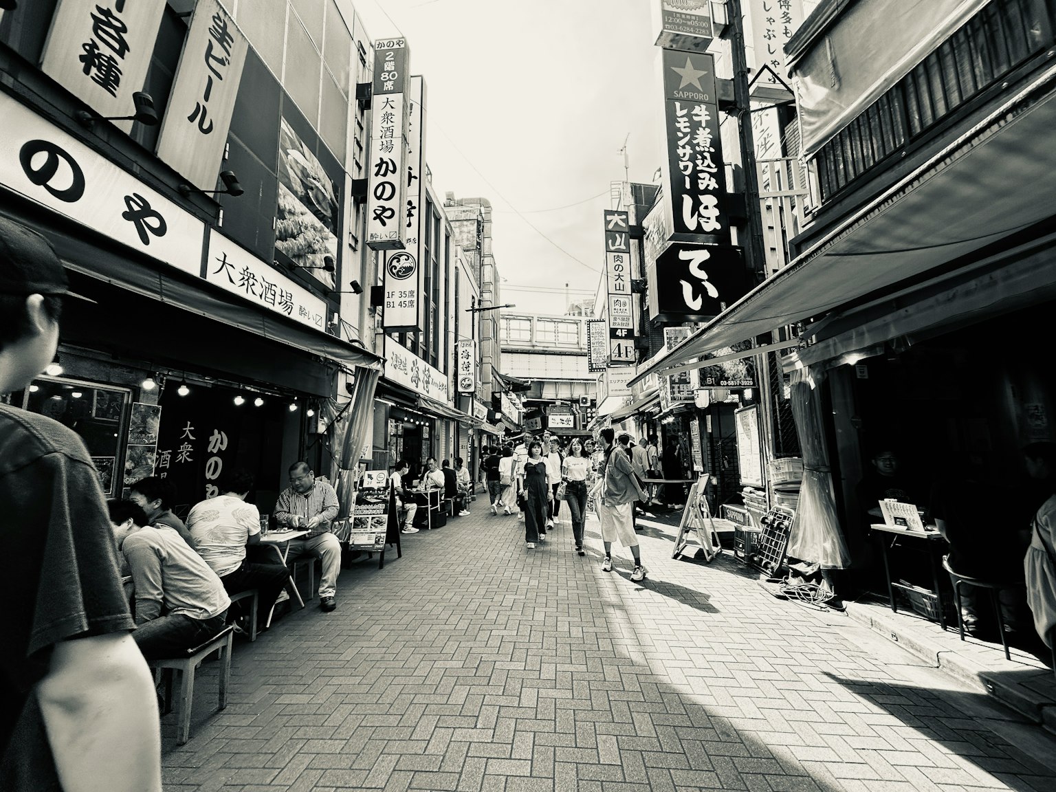 Escena de calle en blanco y negro en Japón con peatones y restaurantes a ambos lados