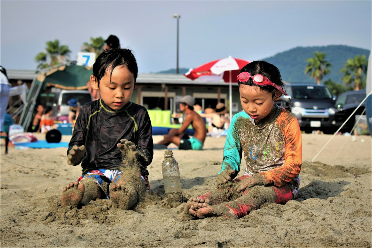 Dua anak bermain di pasir dengan kaki terkubur di pantai