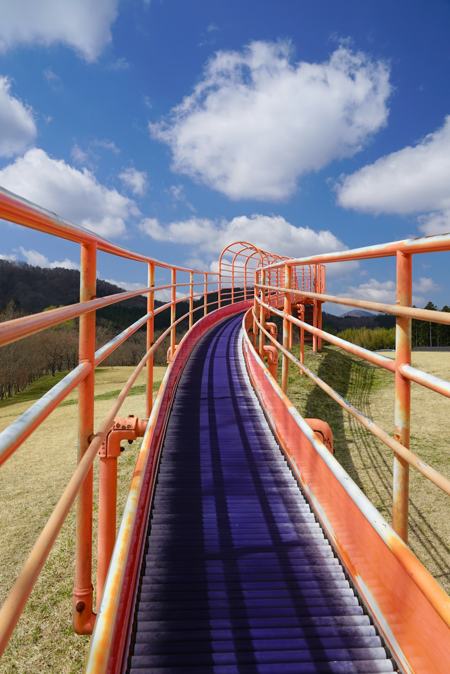 Purple roller coaster track with orange railings and blue sky