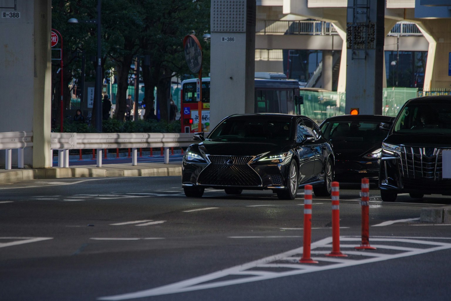 一辆黑色汽车在城市道路上行驶，路旁有交通障碍
