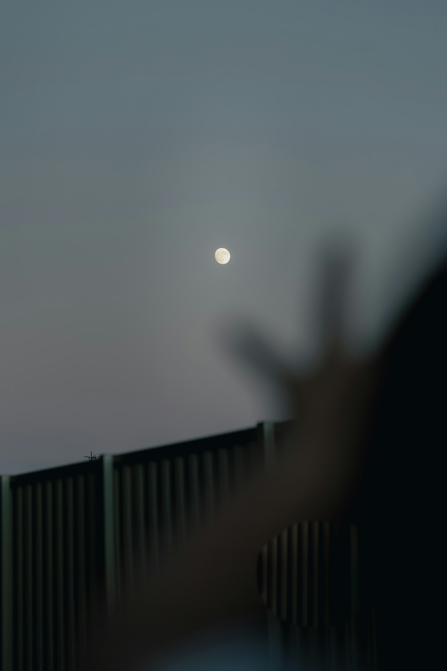 Blurred background with a visible moon and silhouette of a hand