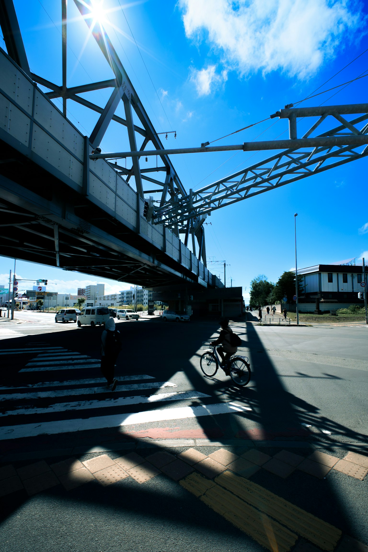 Sous un pont avec l'ombre d'un cycliste sur le passage piéton sous un ciel bleu clair
