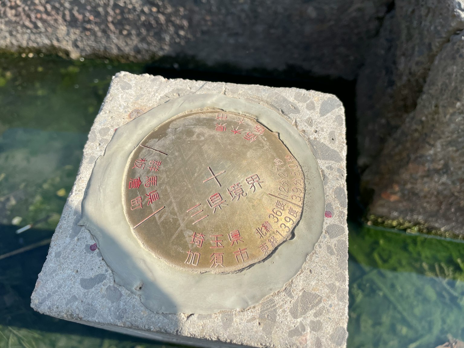 Metallplatte in einer Betonbasis mit sichtbaren Markierungen eingebettet