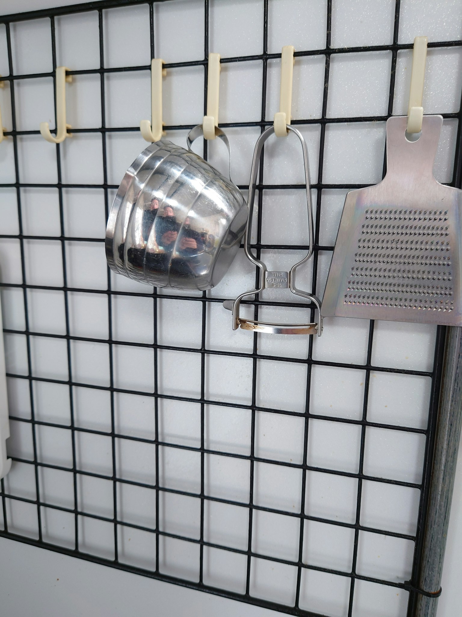 Set di utensili da cucina appesi su una griglia a muro