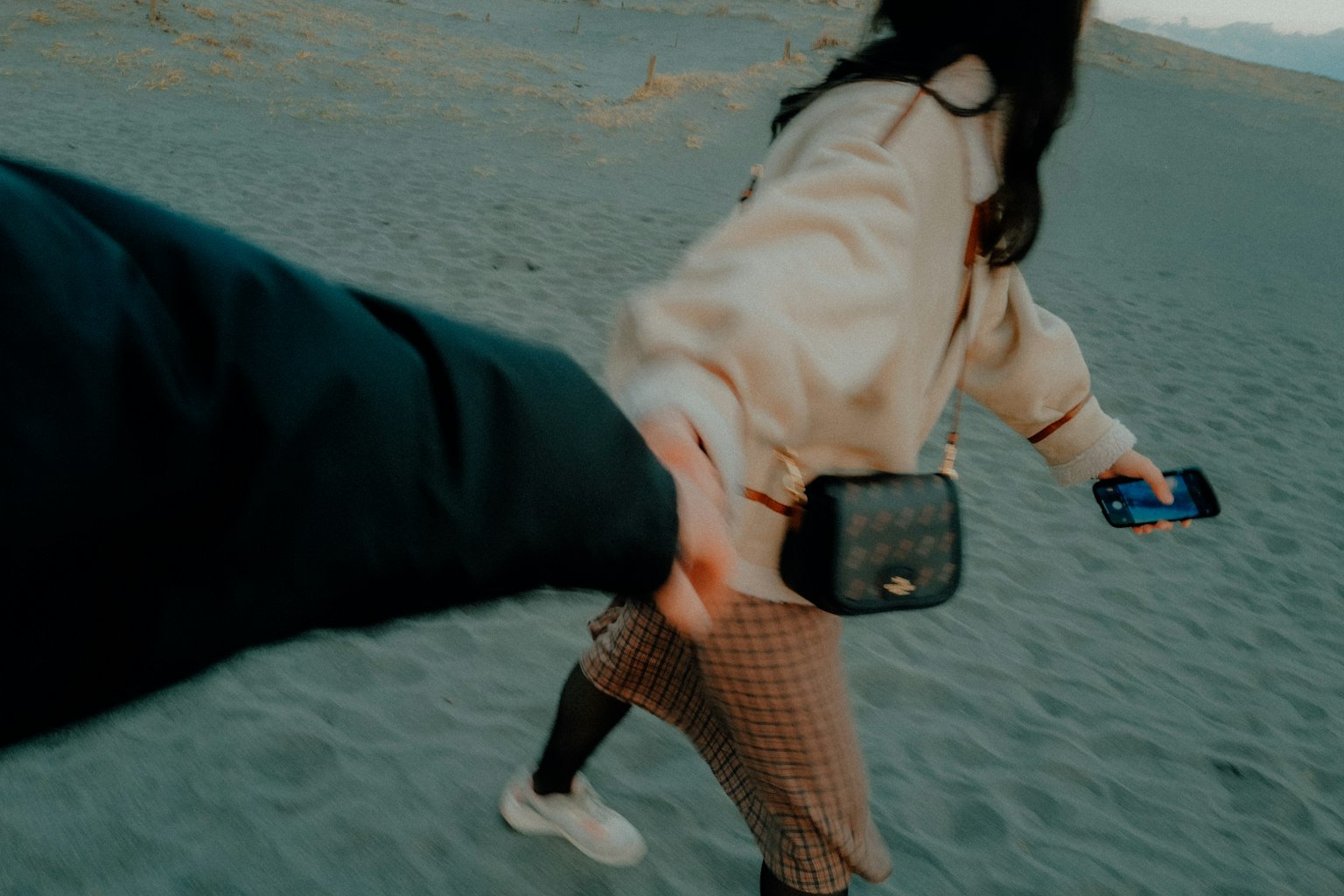 Pasangan yang bergandeng tangan saat berjalan di pantai berpasir
