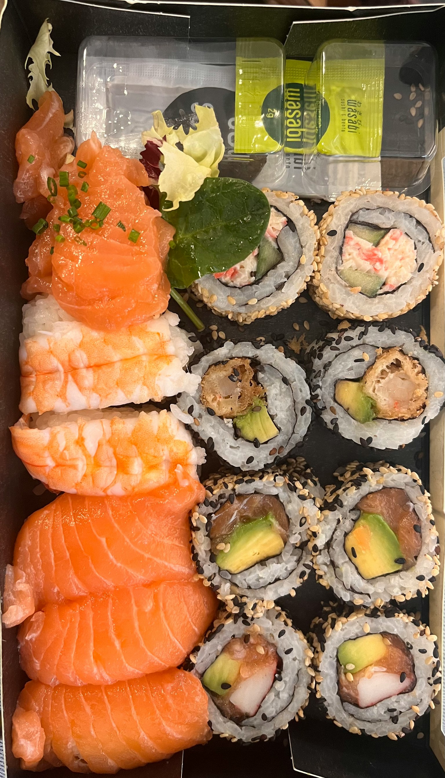 Sushi platter featuring salmon sashimi and various sushi rolls