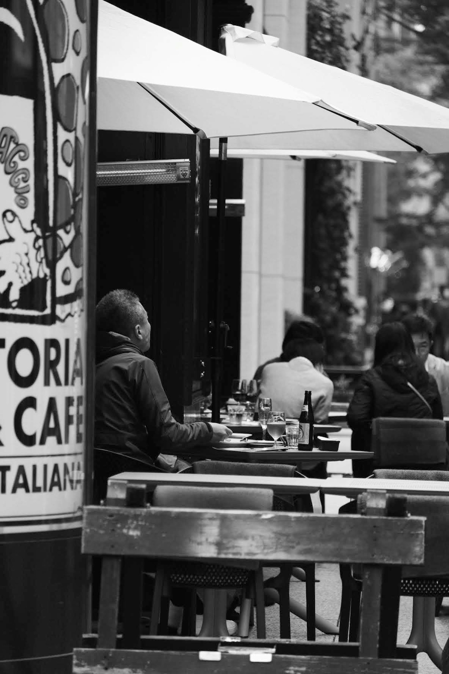 ภาพขาวดำของผู้คนที่นั่งอยู่ที่ระเบียงร้านกาแฟ