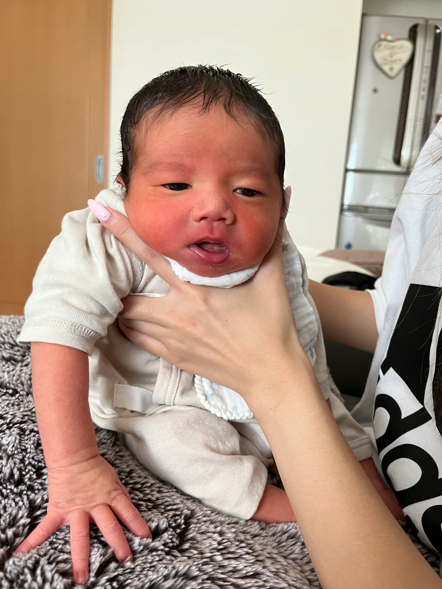 Un bambino tenuto con un vestito bianco con una mano che sostiene il suo mento