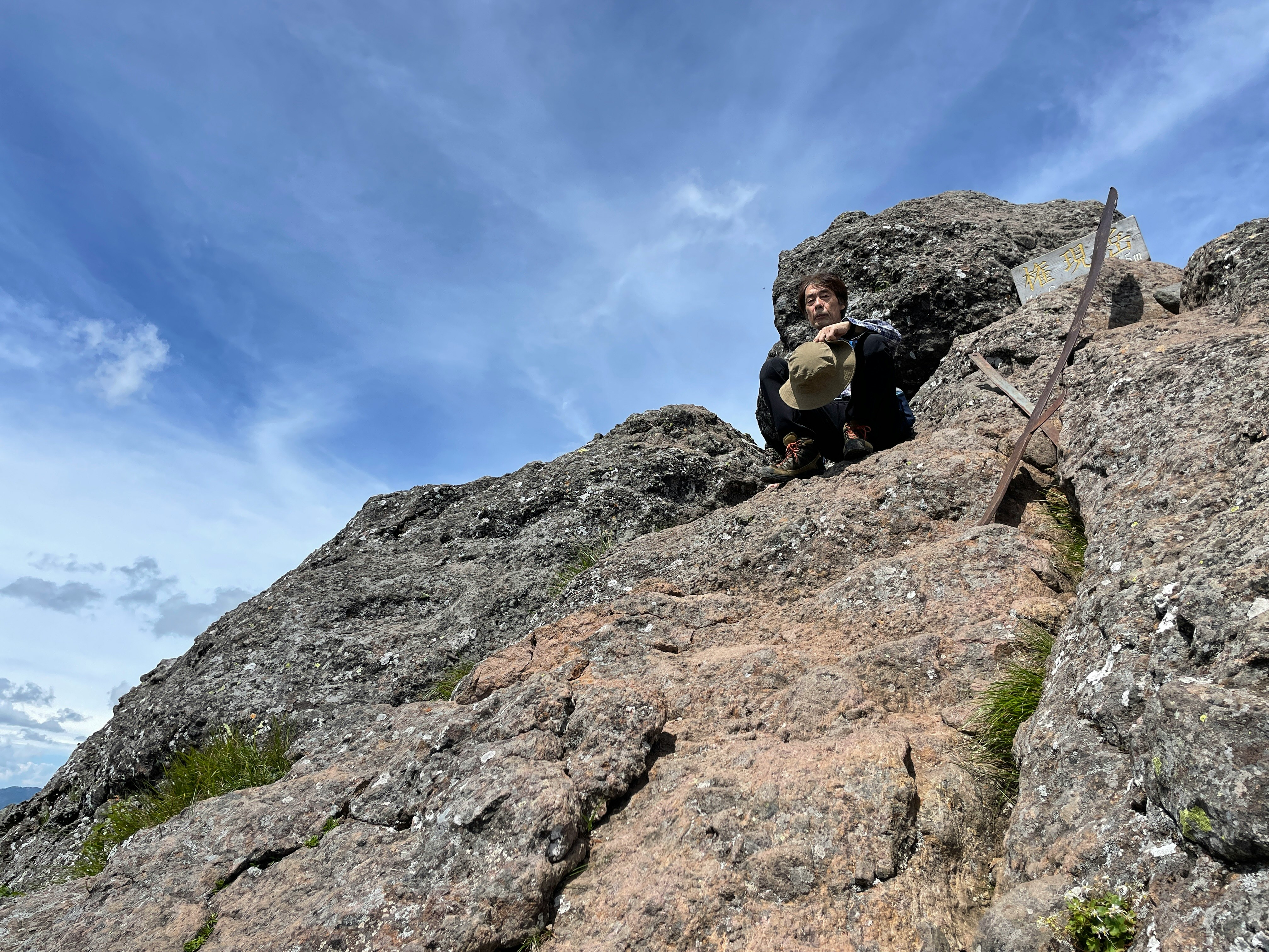 hiker climbing rocky mountain slope under blue sky