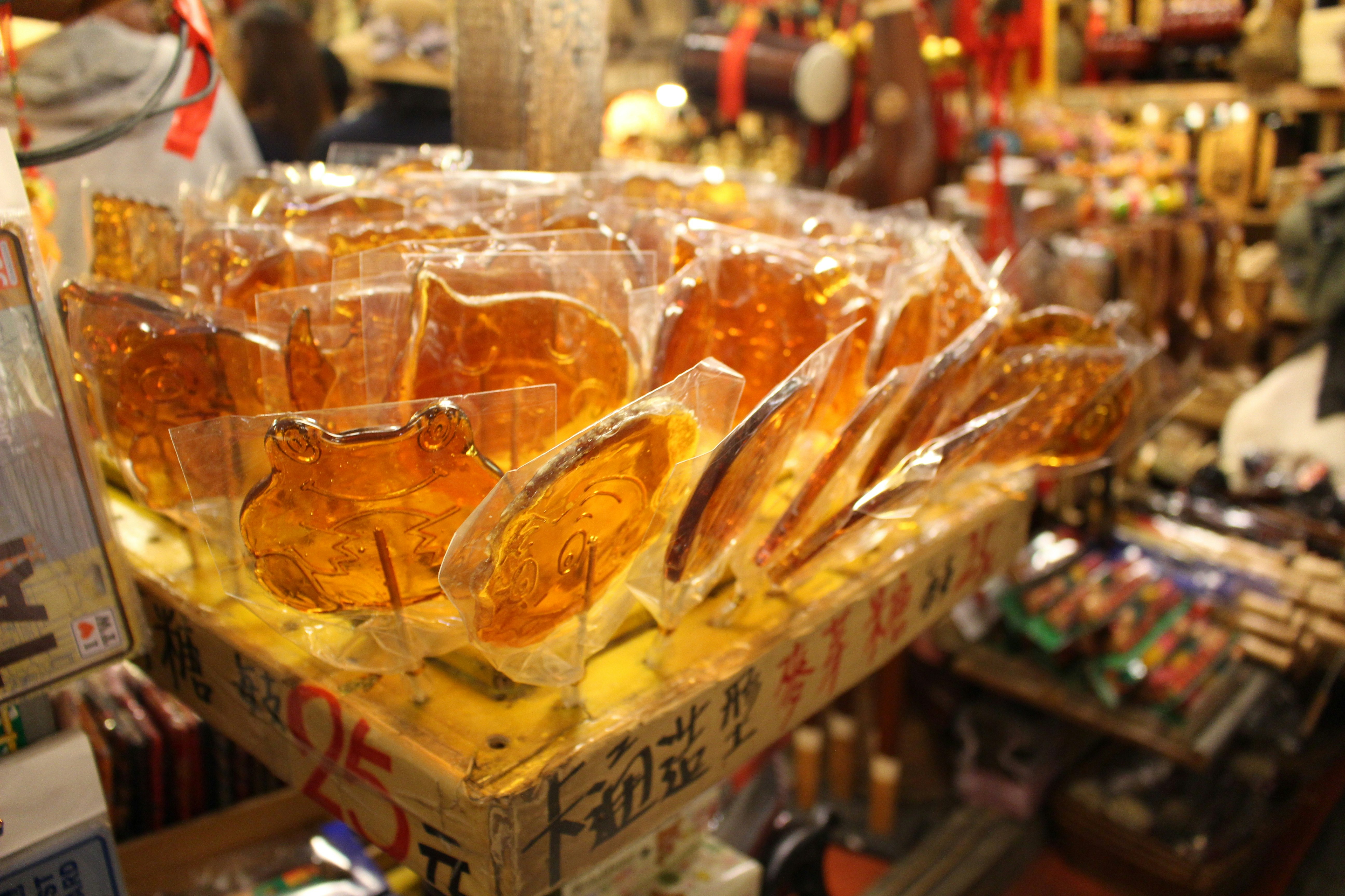 透明な袋に入った琥珀色の飲料やお菓子が並ぶ店頭