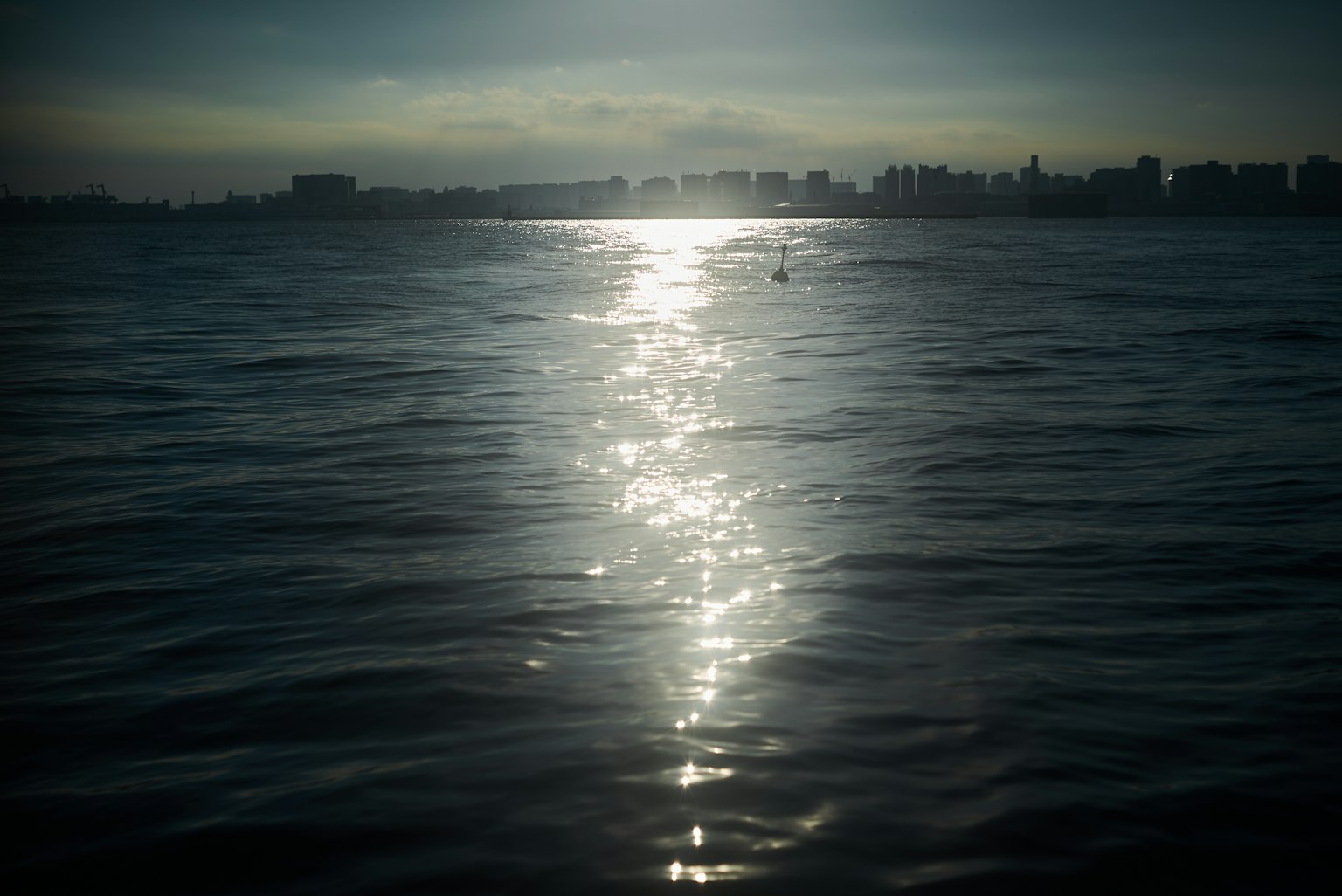 Reflet de lumière sur l'eau avec une silhouette de ville sombre en arrière-plan