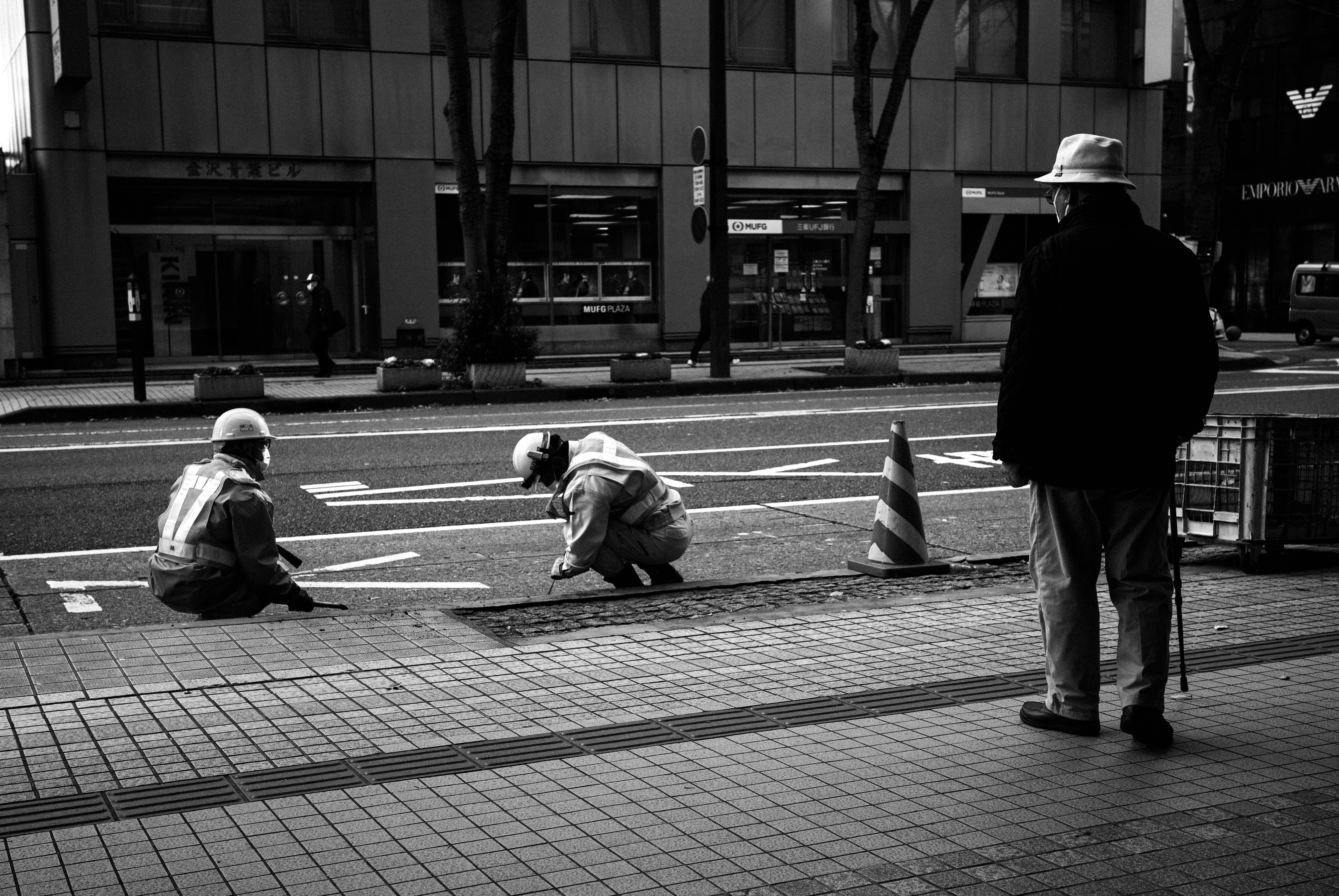 路上で作業する人と三脚のある街角