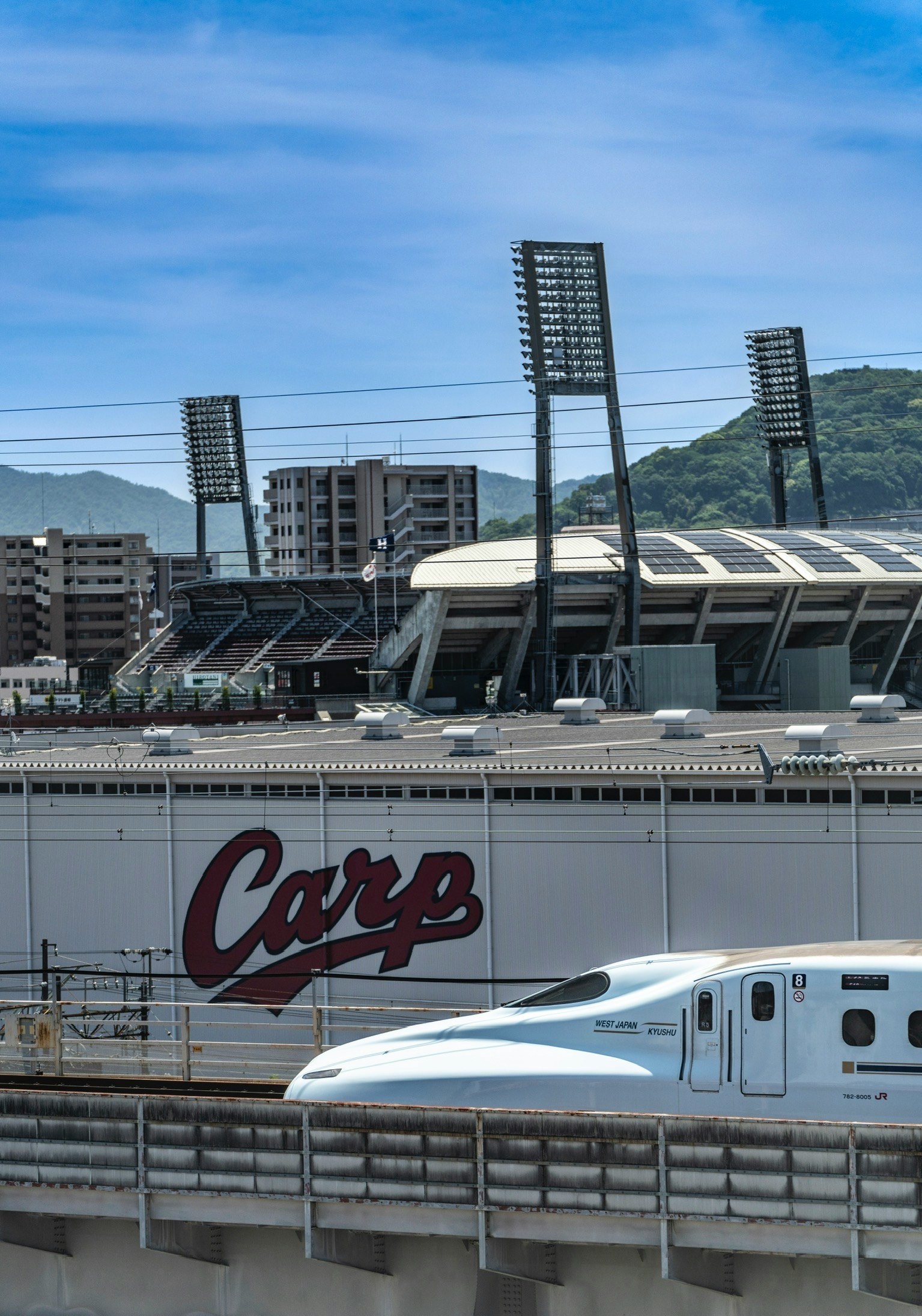 「CARP」ロゴの新幹線が走る高架駅の風景