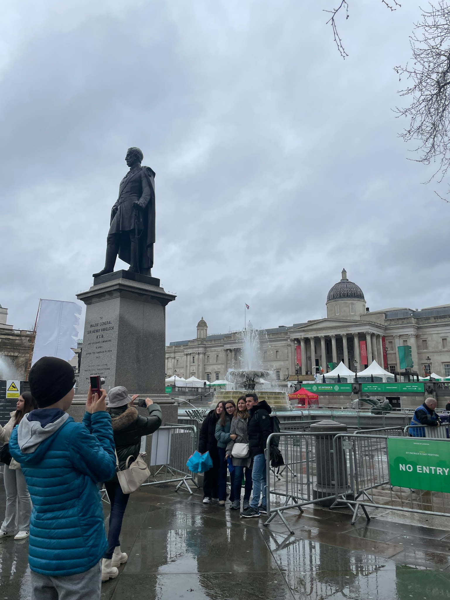 Statue von Admiral Nelson auf dem Trafalgar Square mit Besuchern und bewölktem Himmel