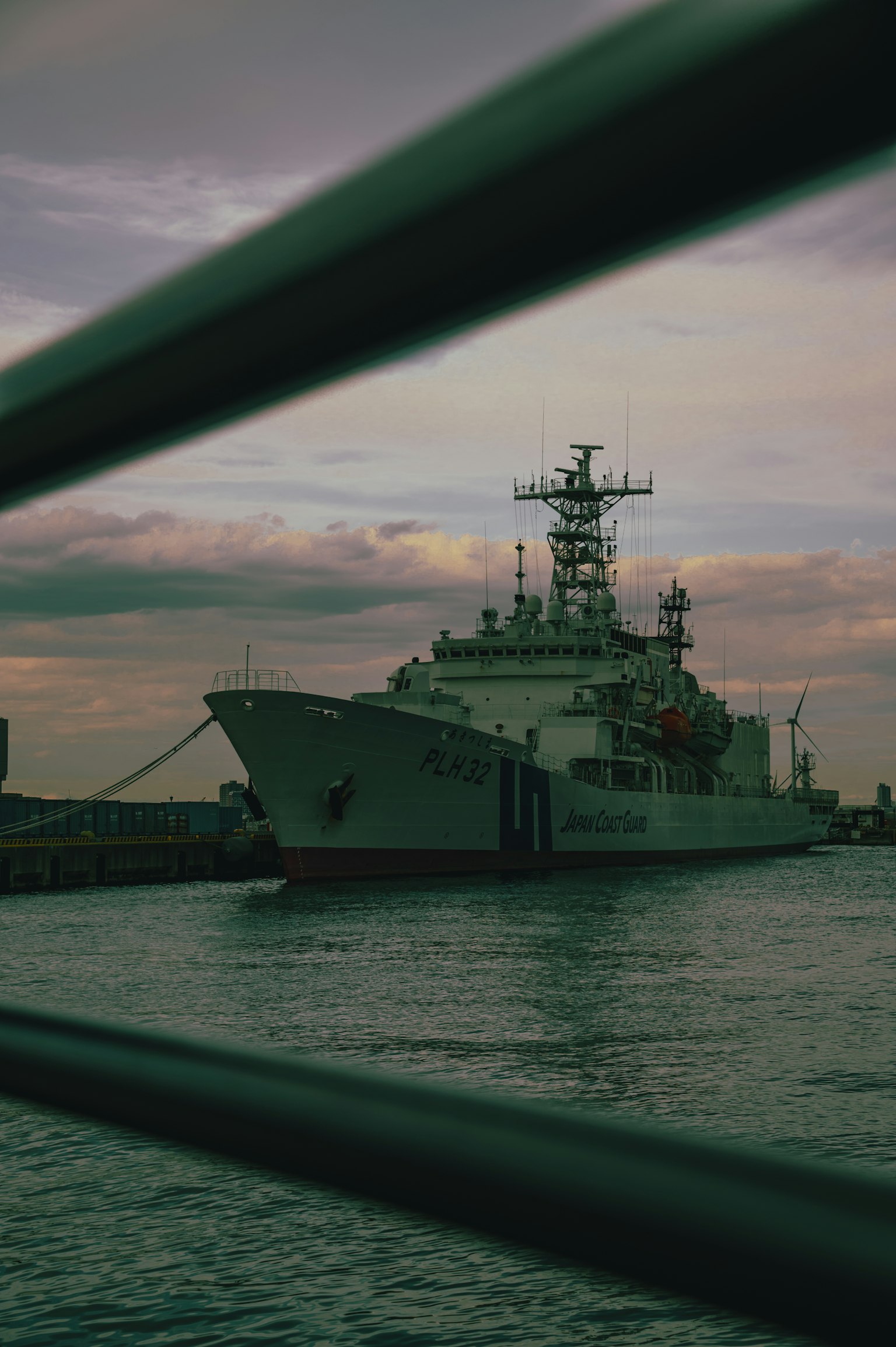 Un navire de guerre amarré dans un port avec un ciel nuageux et de l'eau calme