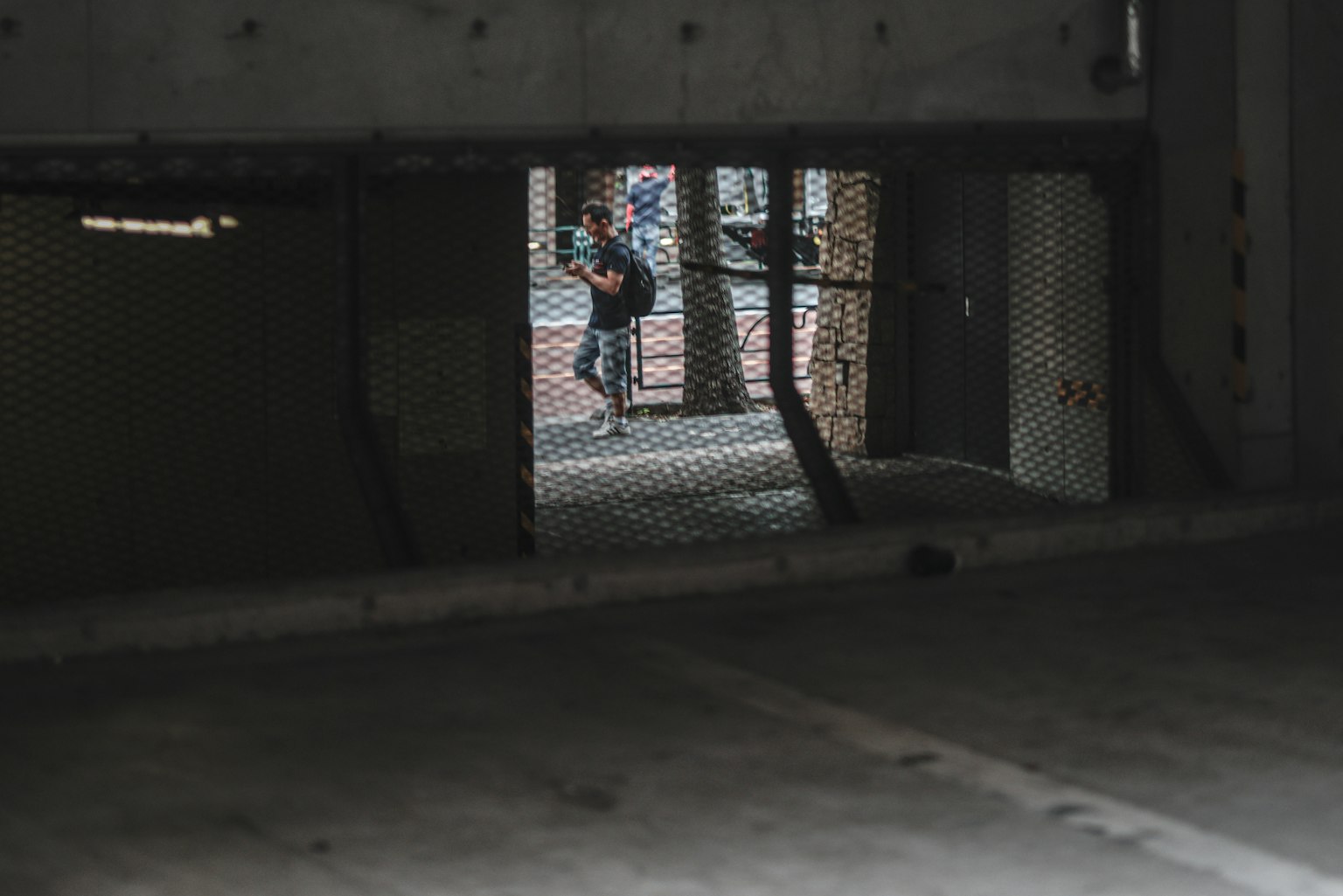 View of a street and a person through a concrete wall and wire mesh