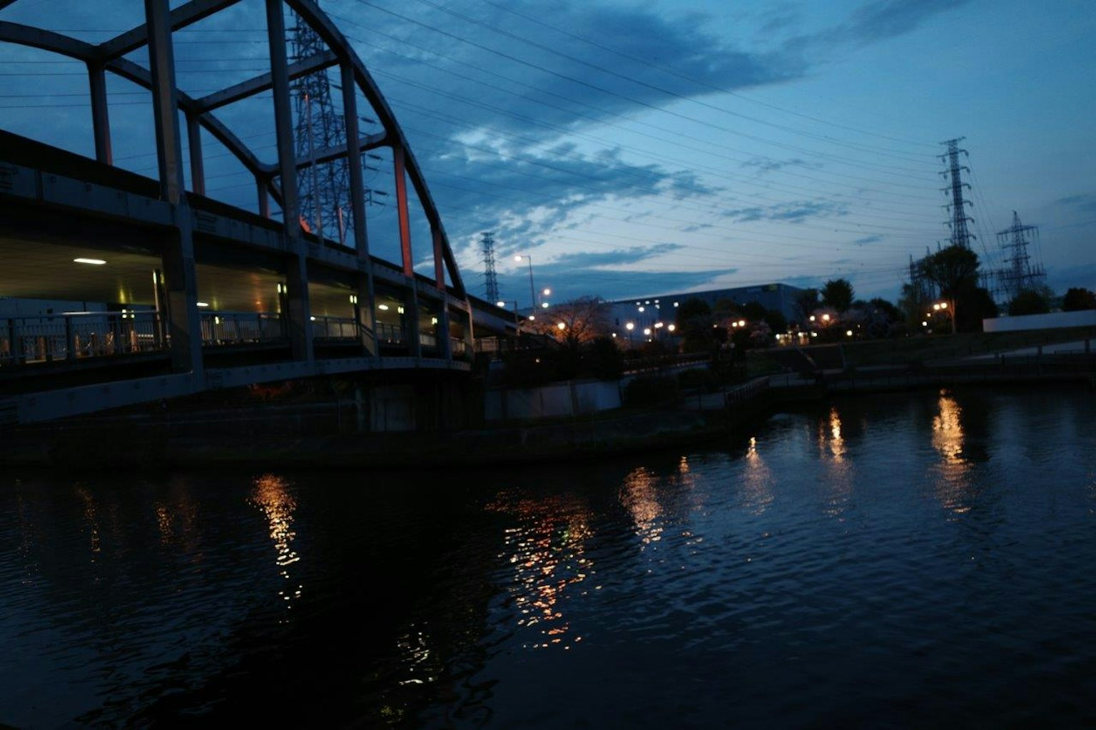Vista notturna di un ponte e di un fiume con luci della città che si riflettono