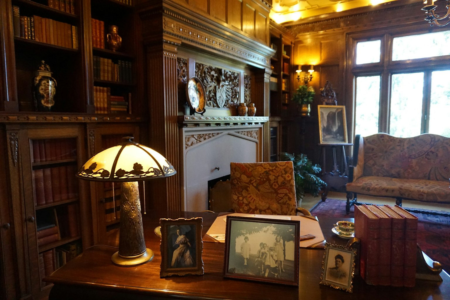 Klassisches Holzstudium mit Regalen und Kamin, ausgestattet mit antiken Möbeln und Lampe