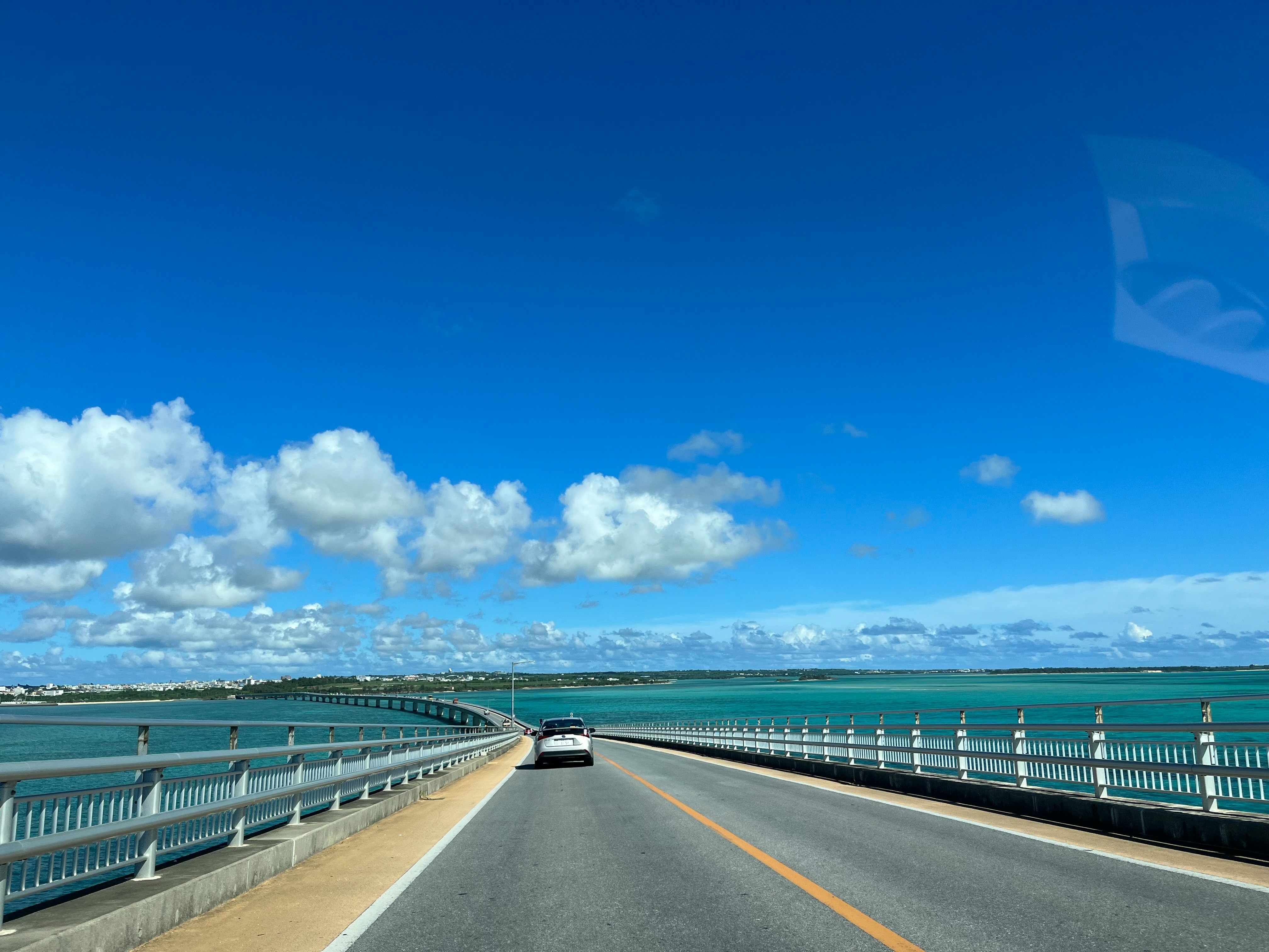青空の下を走る車と伊良部大橋の海上道路