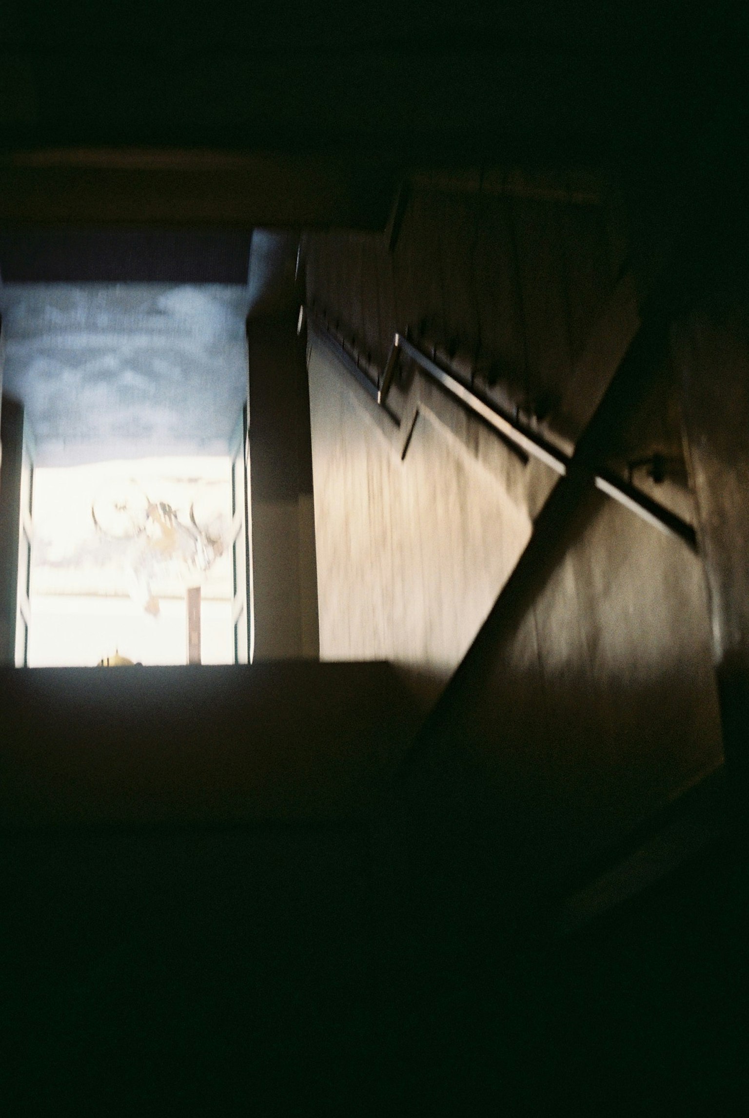 Una vista desde una escalera oscura hacia una puerta abierta con luz que entra