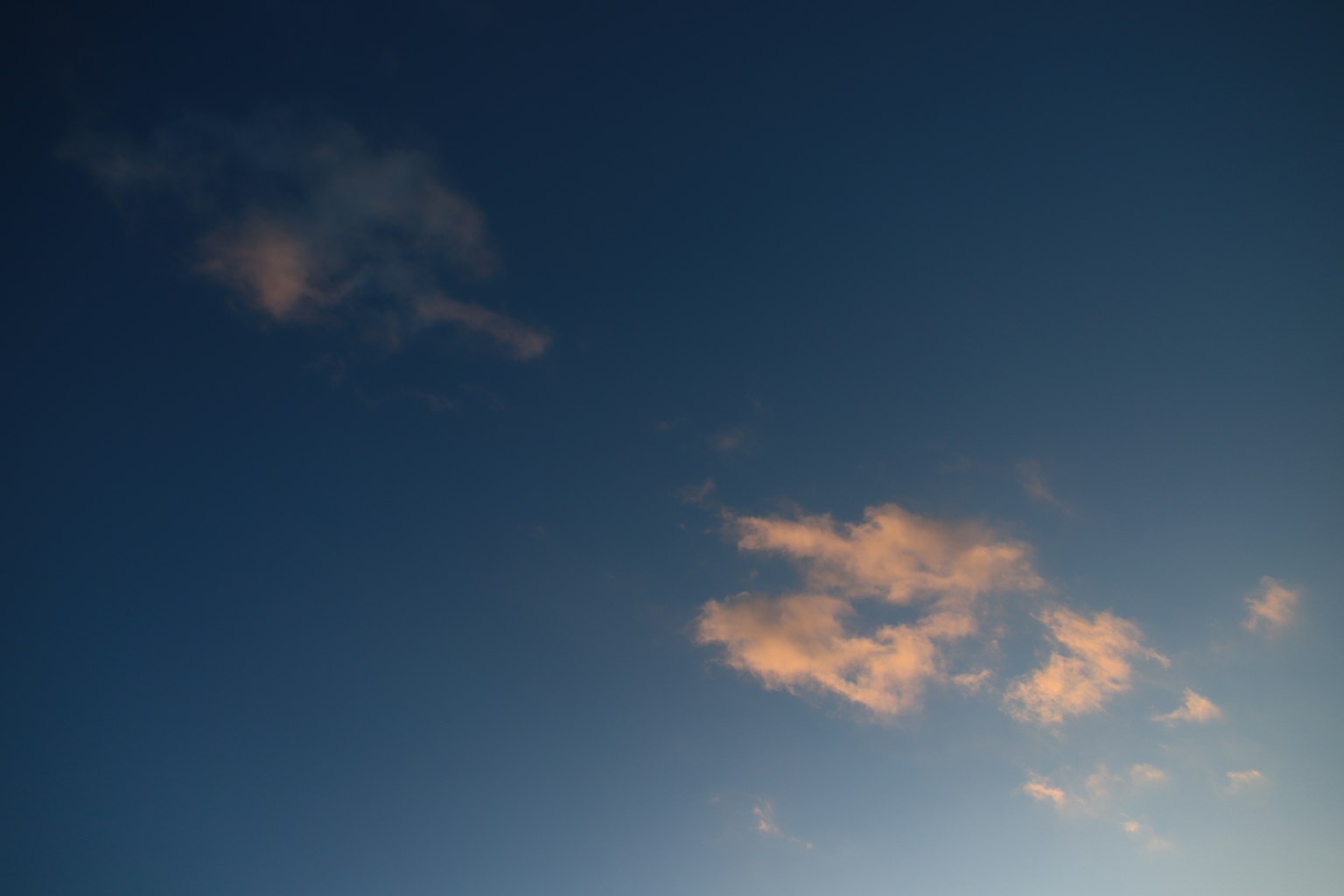 Soft clouds against a deep blue sky at dusk