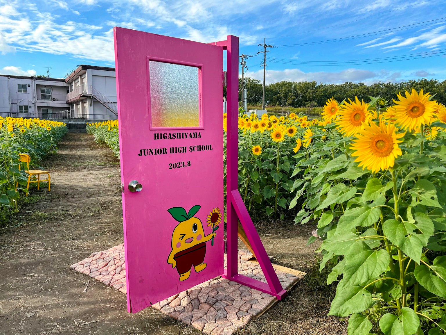Una puerta rosa con un personaje de limón en un campo de girasoles