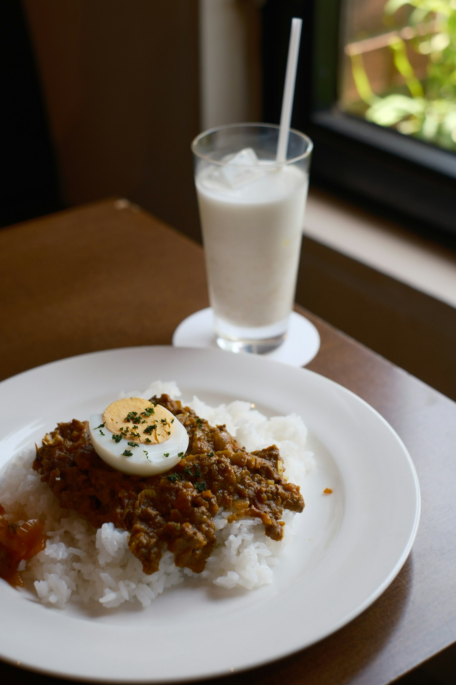 白ご飯の上に揚げた鶏肉と半熟卵が載った料理と飲み物